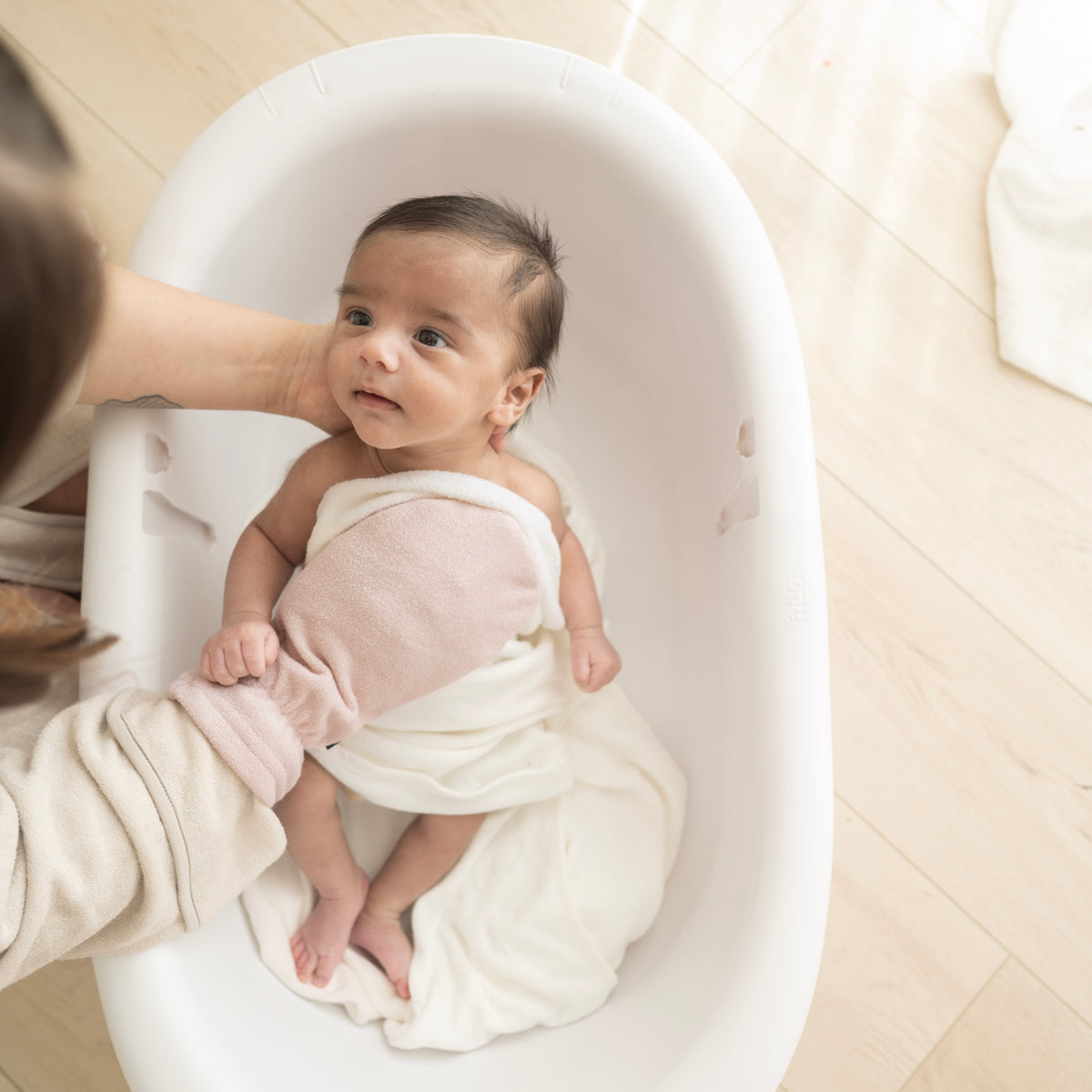 Parent using Bamboo Terry Bath Mitt in Blush to bathe newborn
