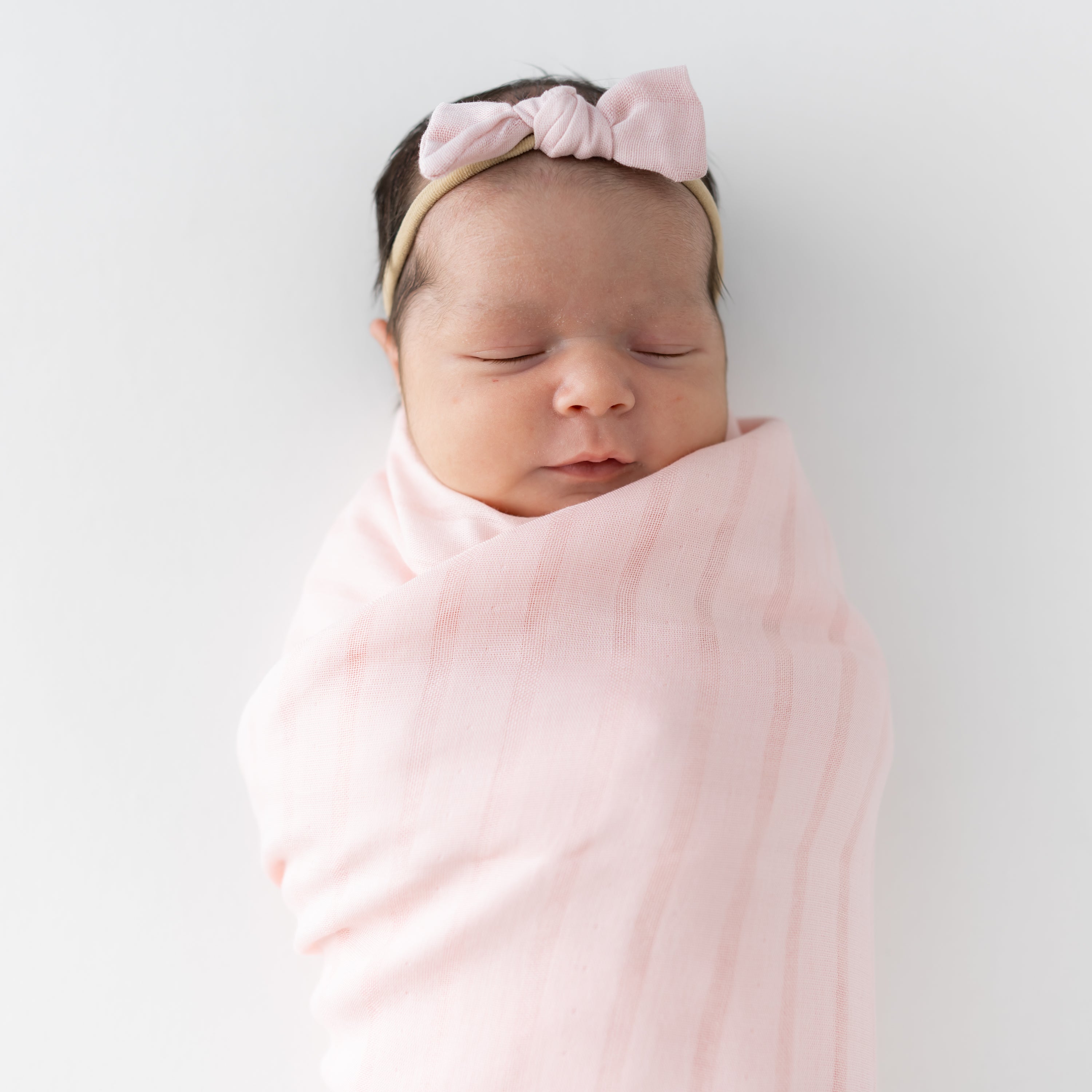 Sleeping newborn wearing a Tiny Muslin Bow in Blush Pink