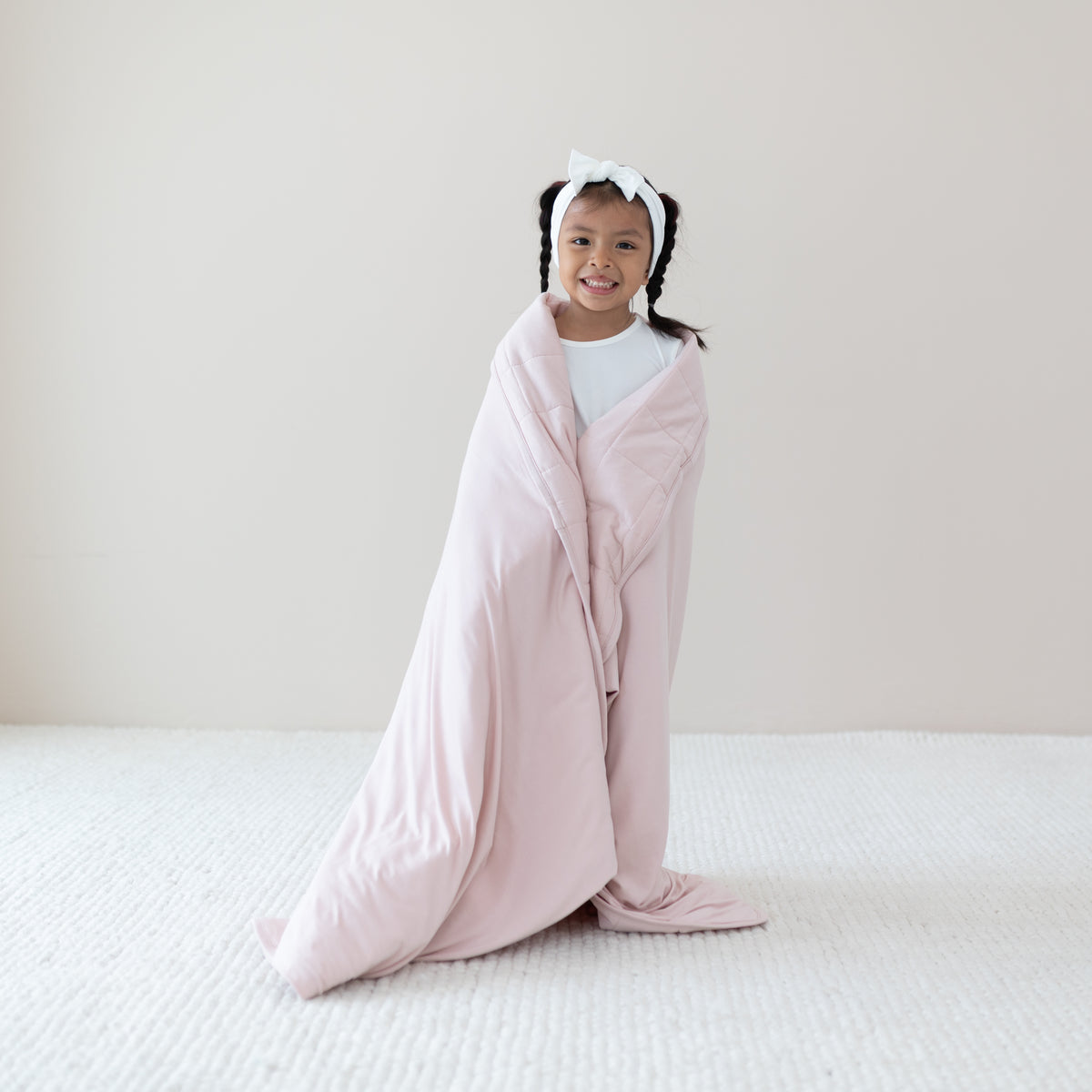 Child in Cloud pajamas wrapped in Youth Blanket in Blush 2.5
