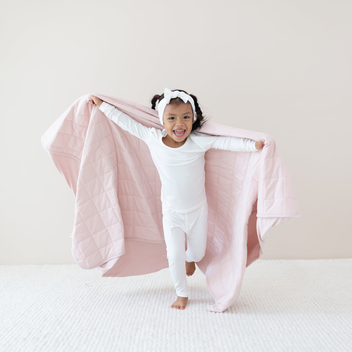 Toddler in Cloud long sleeve pajamas running with Youth Blanket in Blush 1.0