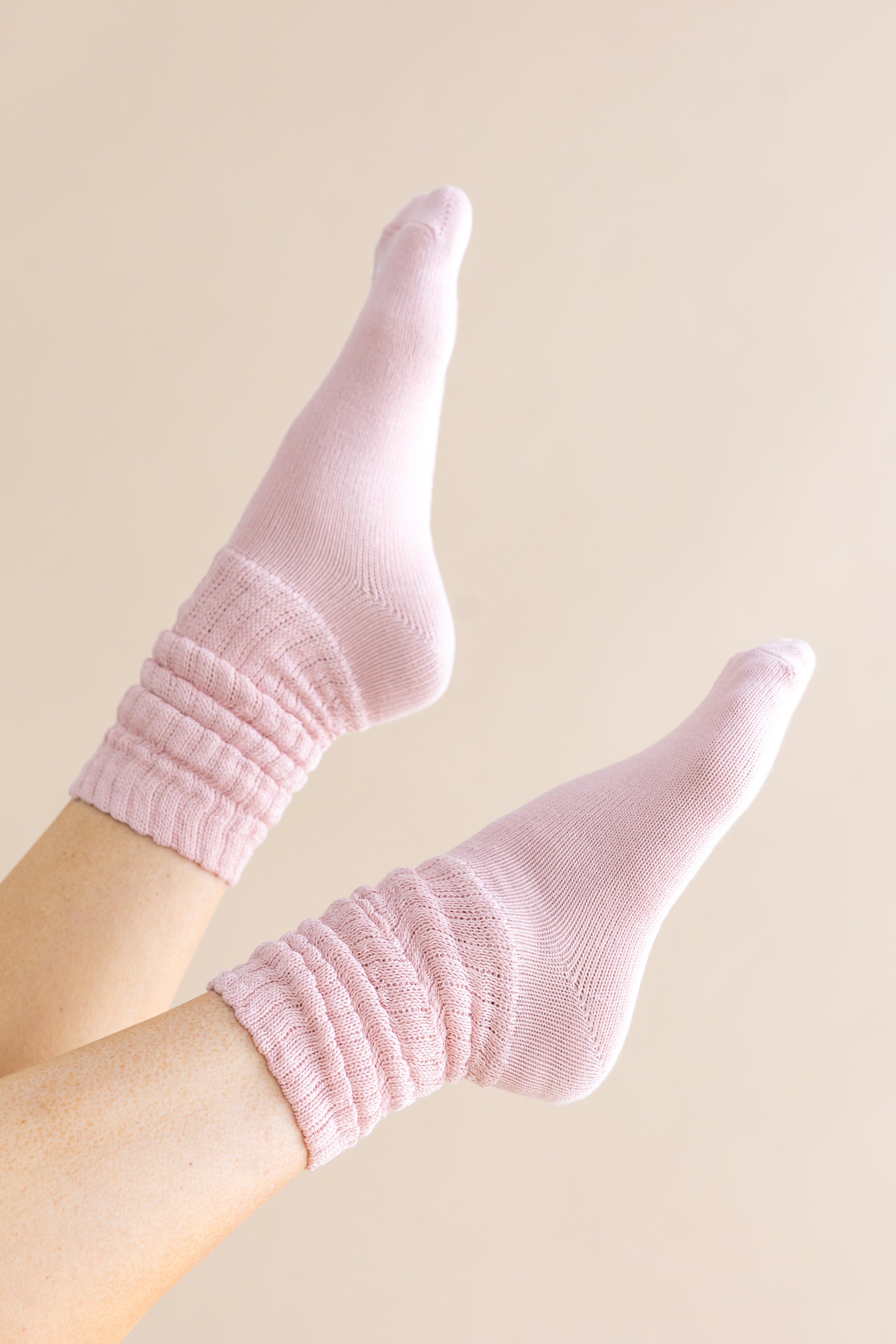 Adult Scrunch Socks in Blush shown on a models feet in the air against a light cream background