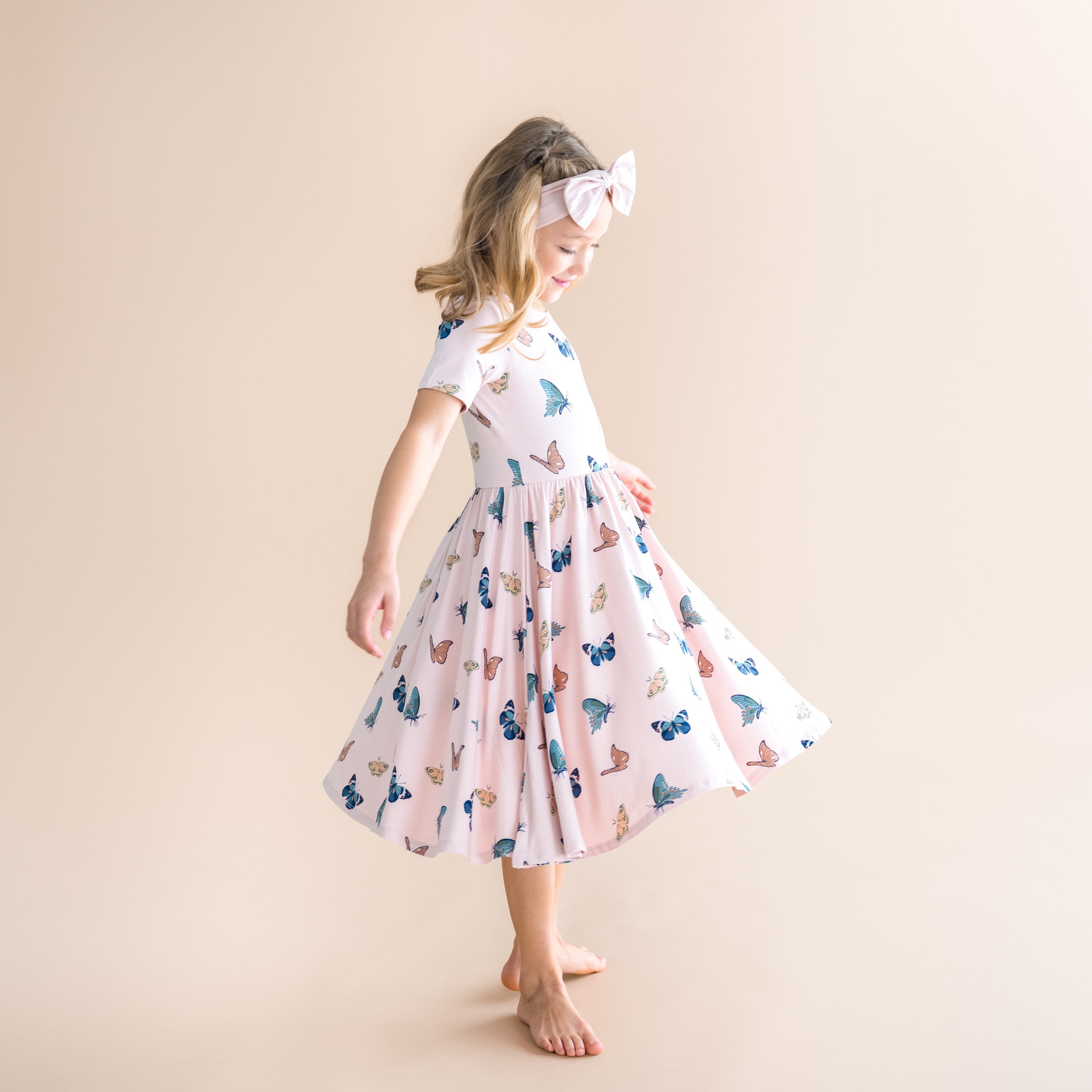 Young girl wearing a butterfly-patterned dress on a beige background