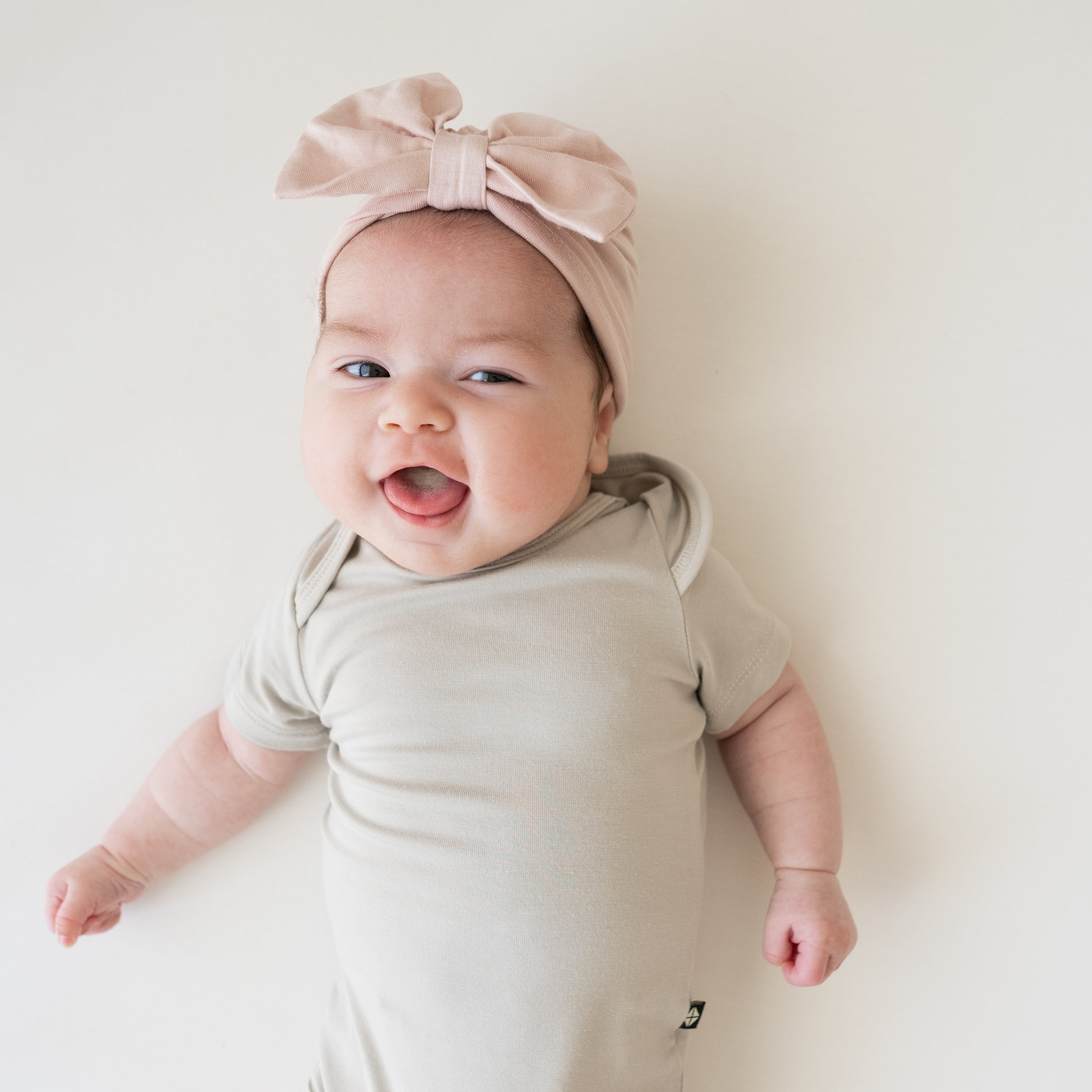 Baby wearing Bow Headwrap in Blush with tan bodysuit