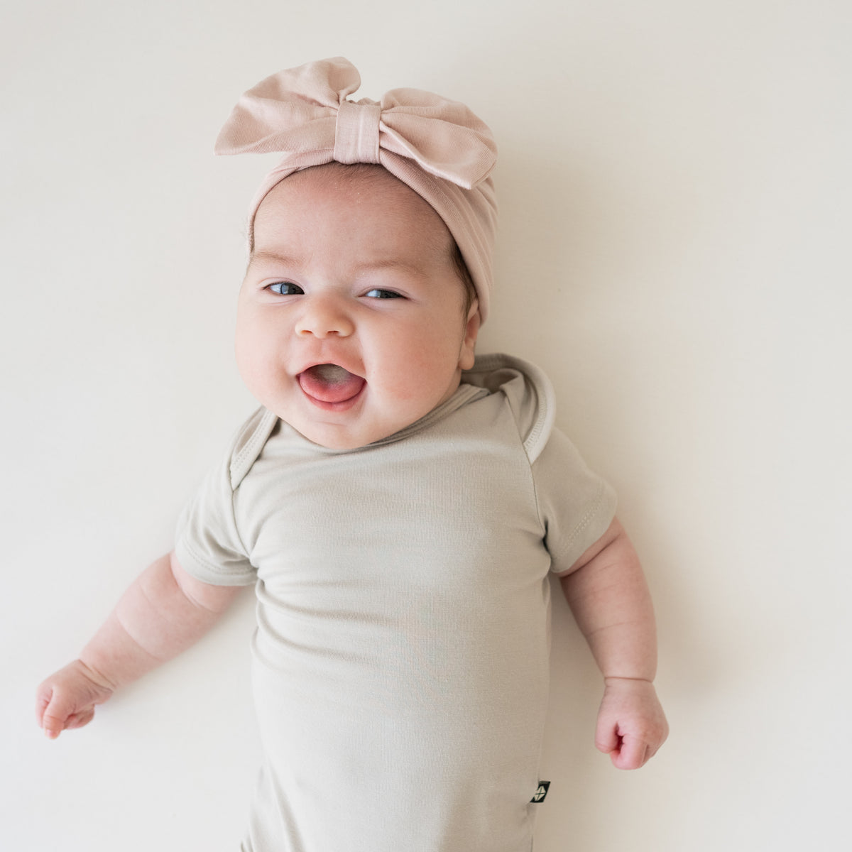 Baby wearing Bow Headwrap in Blush with tan bodysuit