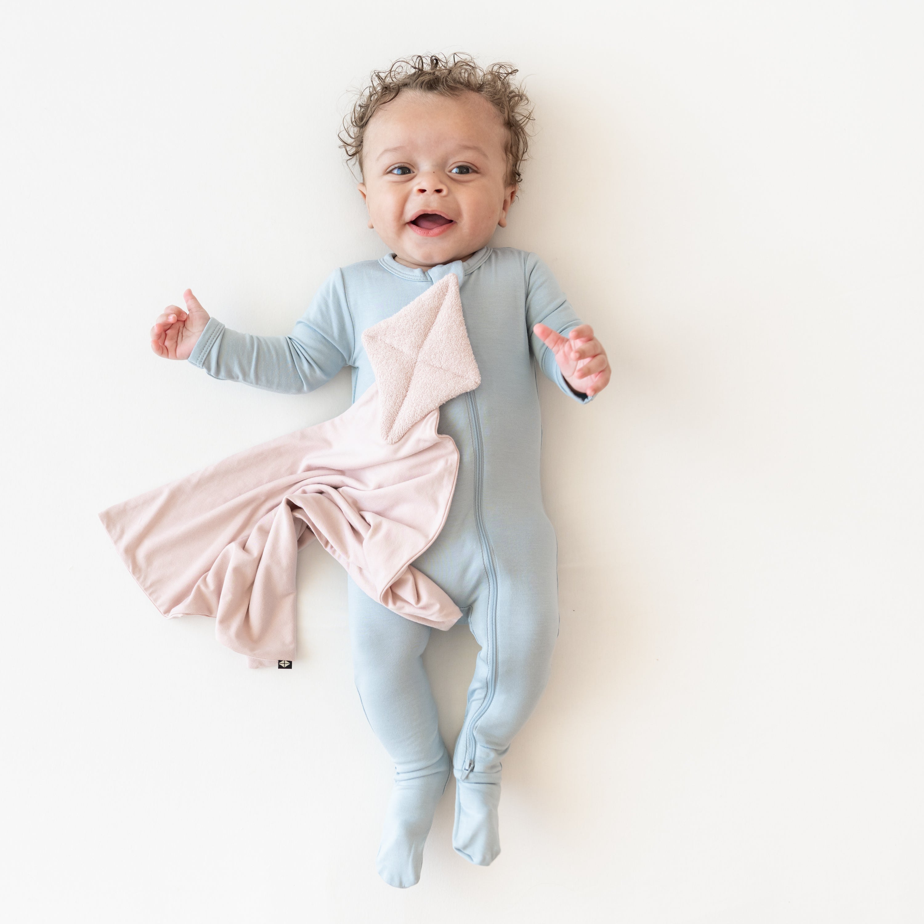 Baby in zippered footie in fog with a Kite Lovey in Blush