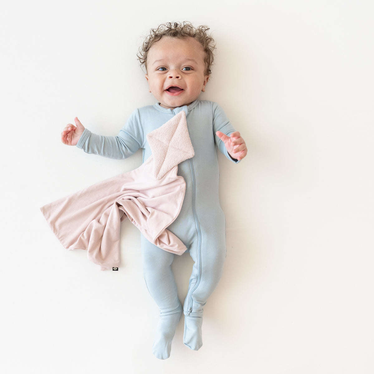 Baby in zippered footie in fog with a Kite Lovey in Blush