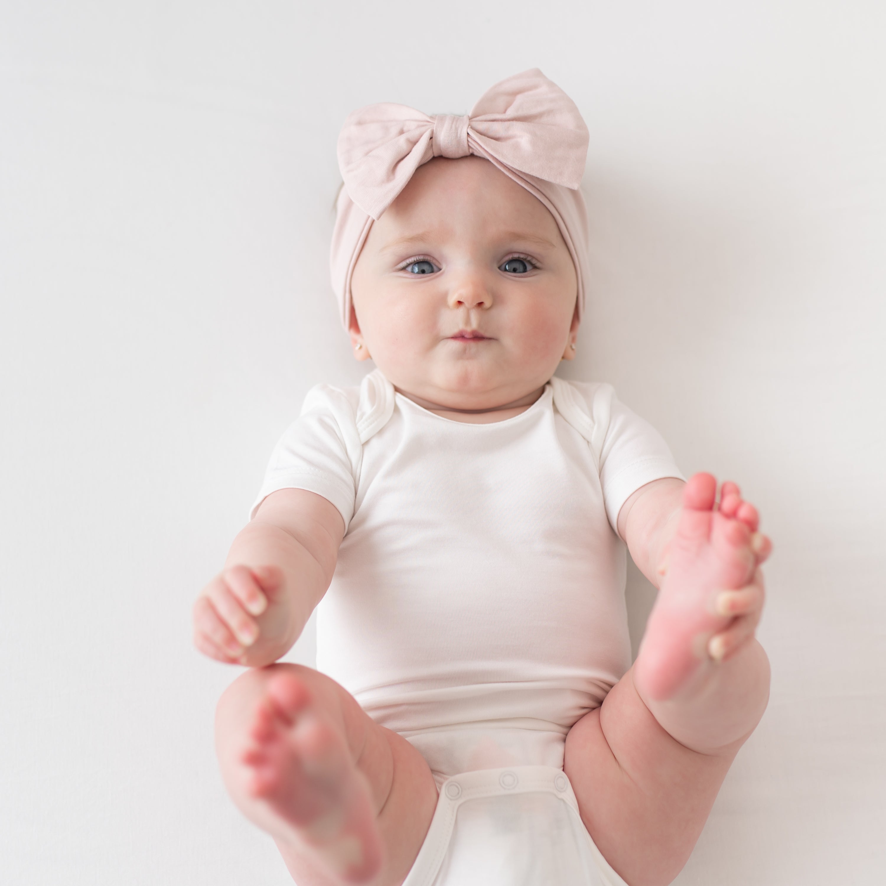 Baby wearing Bow Headband in Blush and Cloud Bodysuit