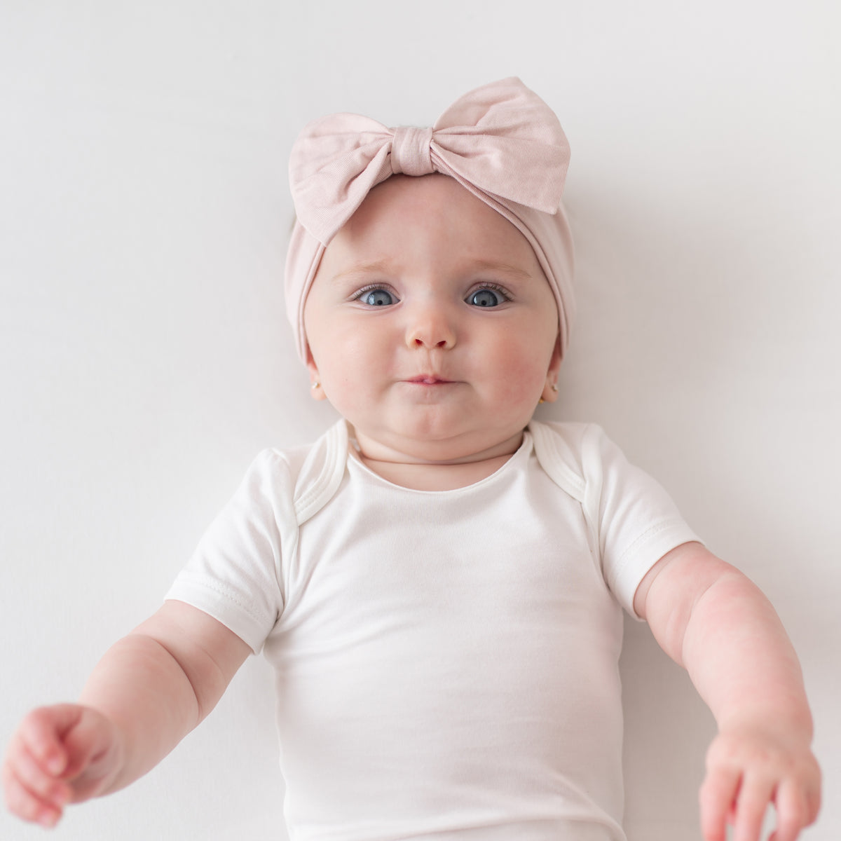 Baby wearing Bow Headband in Blush and Cloud Bodysuit