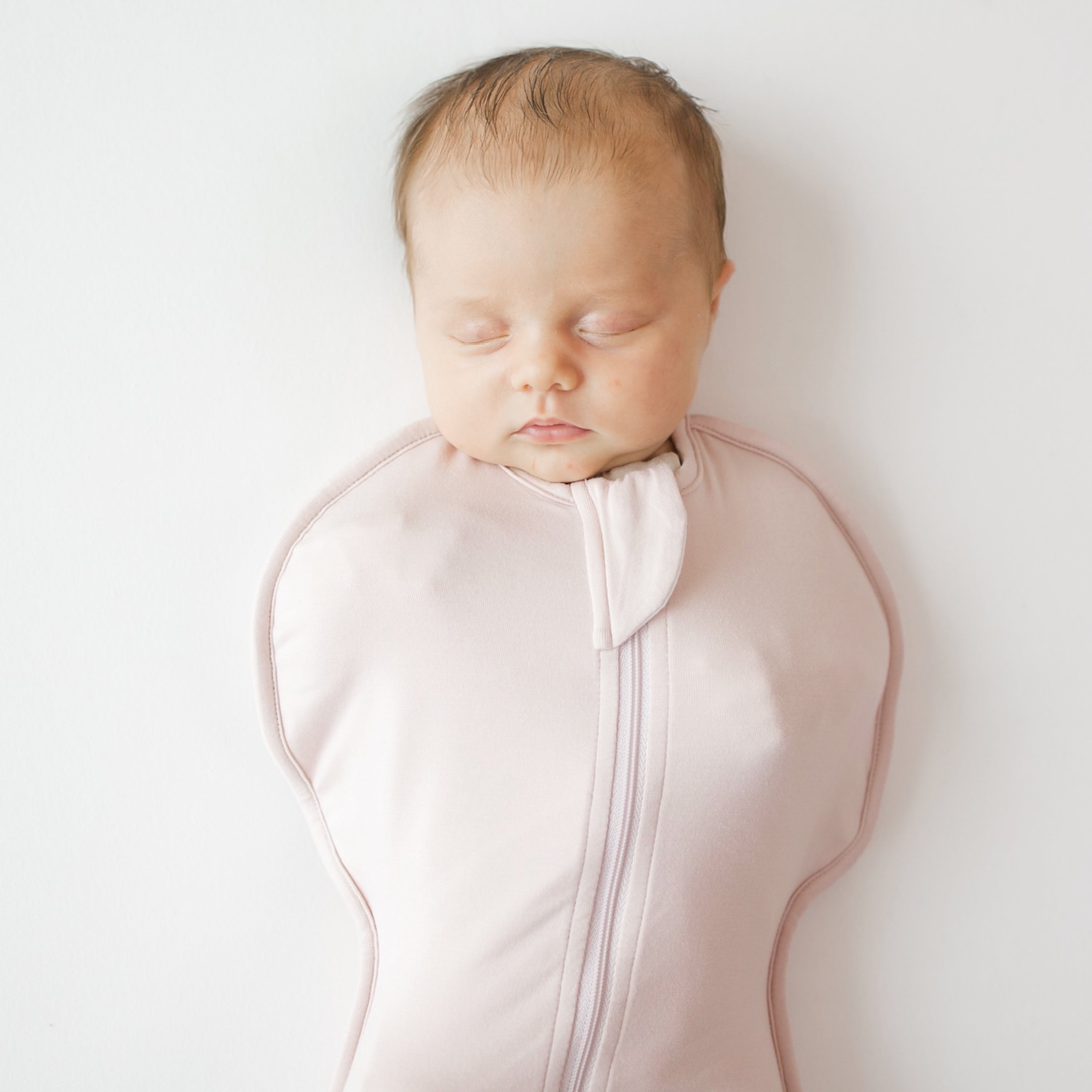 Close up on baby asleep in Kyte Baby Swaddle Bag in Blush 0.5