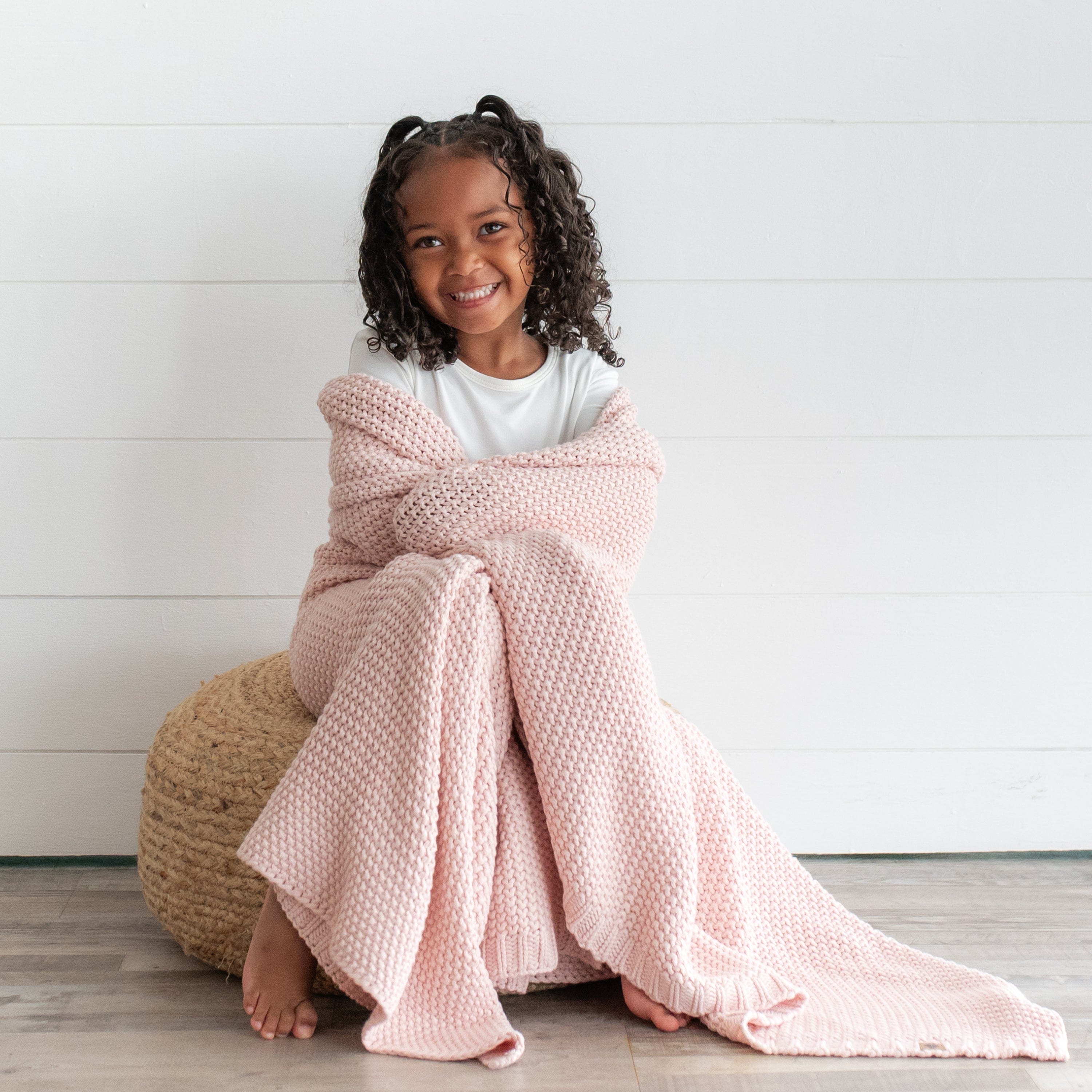 Toddler wrapped in a chunky knit blush blanket