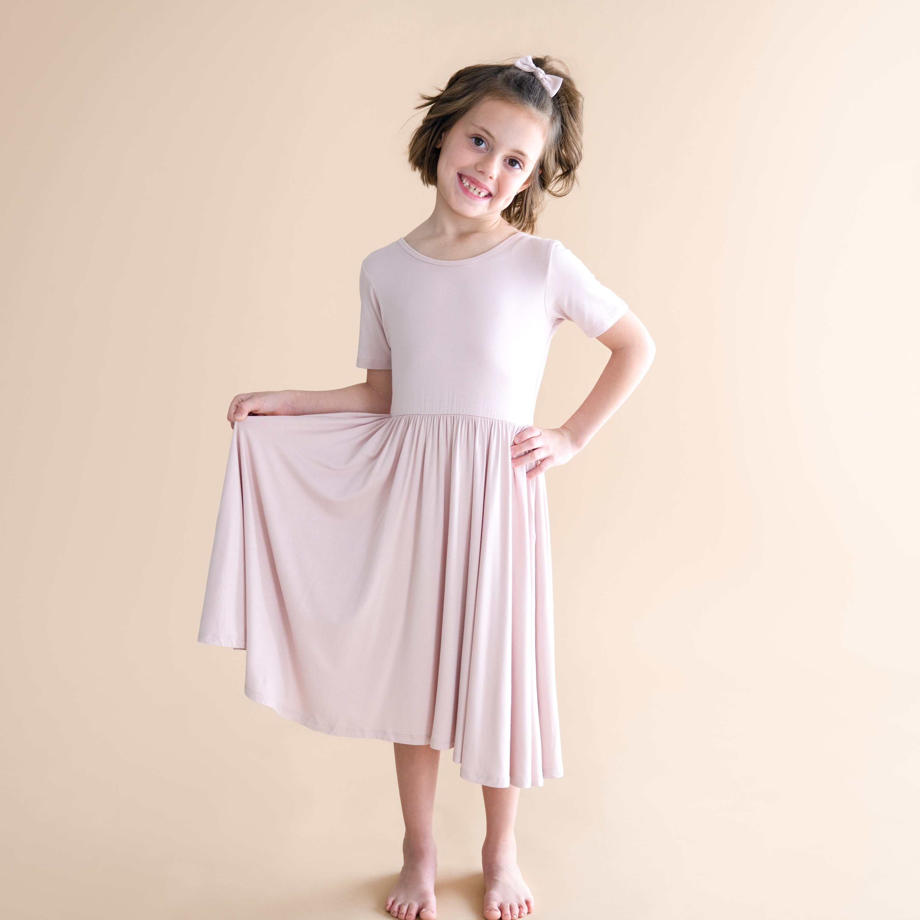 Young girl wearing a light pink dress against a beige background