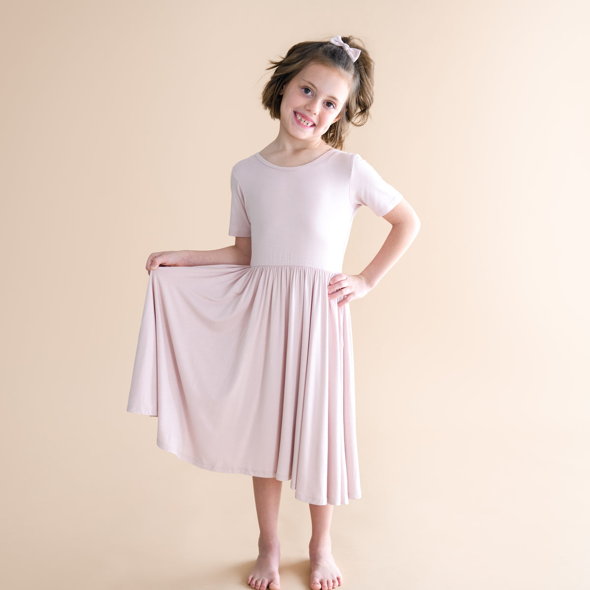 Young girl wearing a light pink dress against a beige background