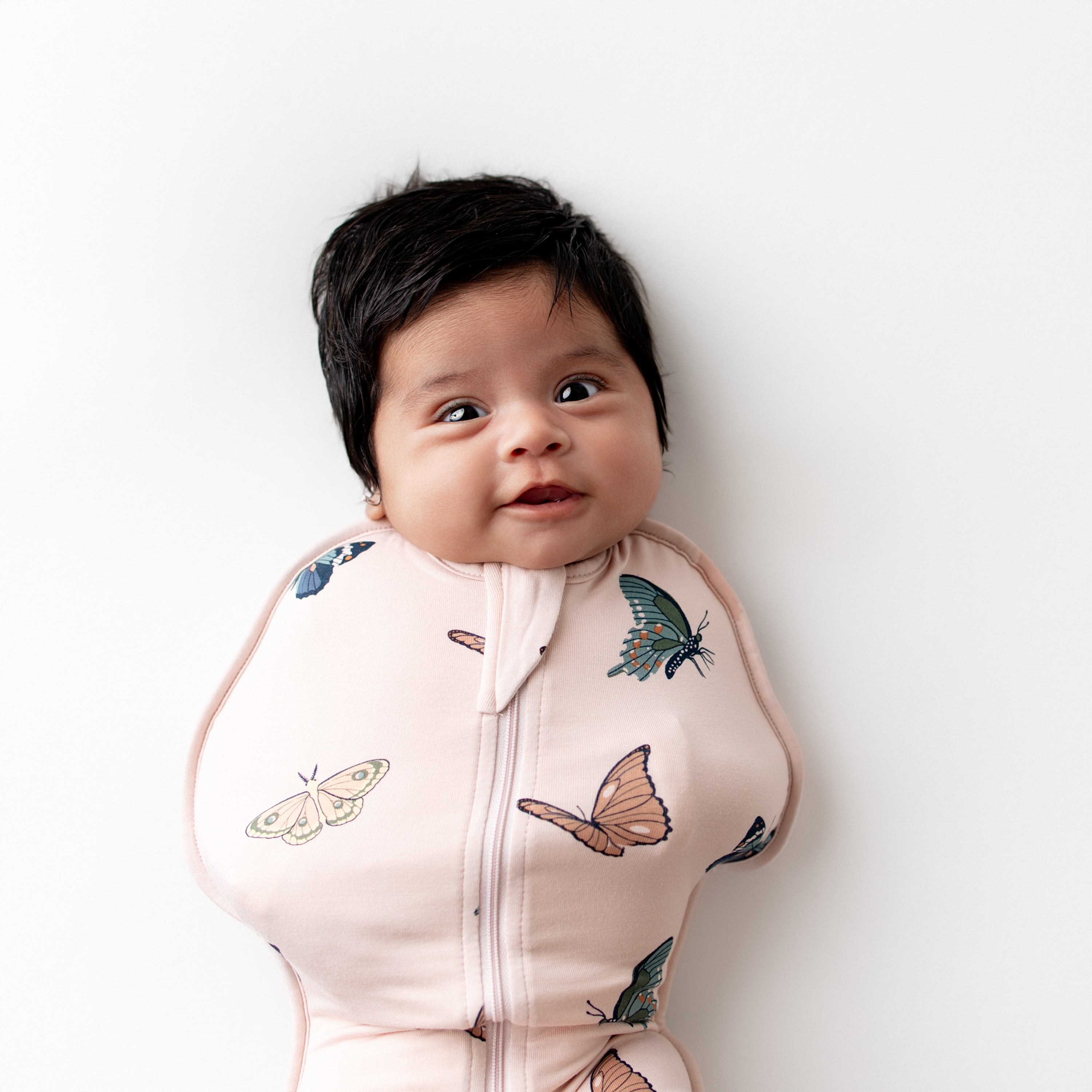Close up of an infant wearing the Swaddle Bag in Blush Butterfly 0.5