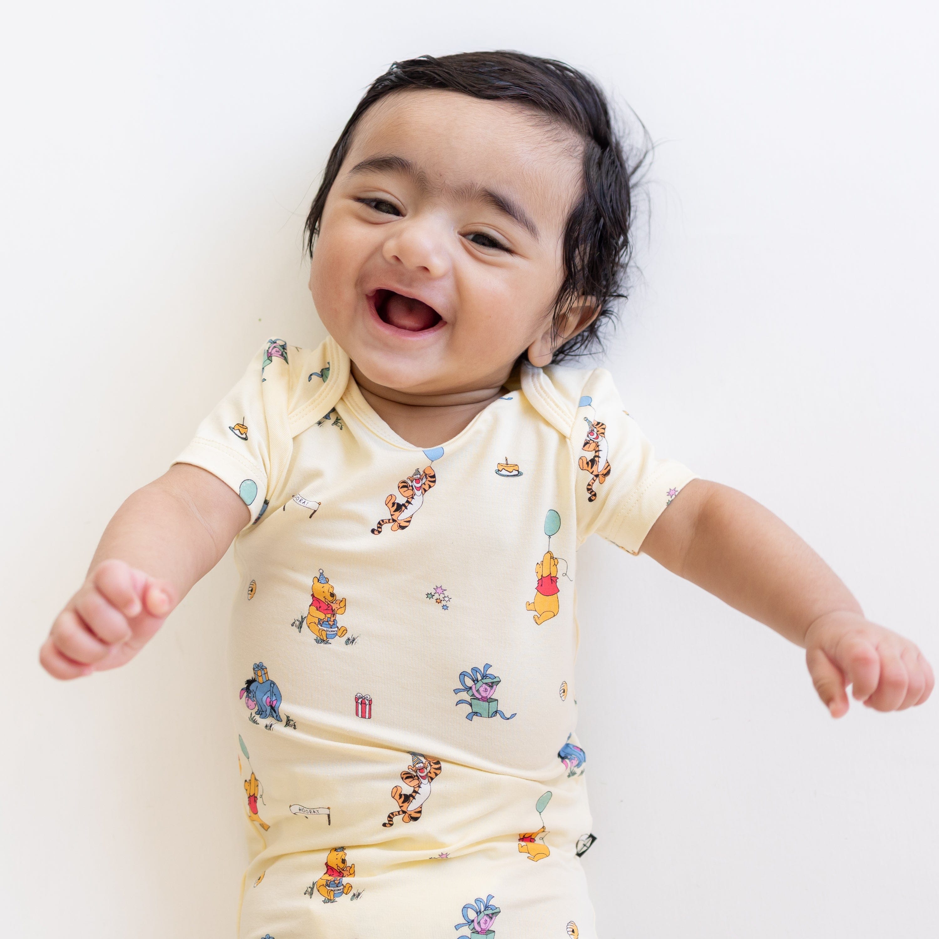 Close up of the Bodysuit in Winnie the Pooh Celebration shown on a smiling baby