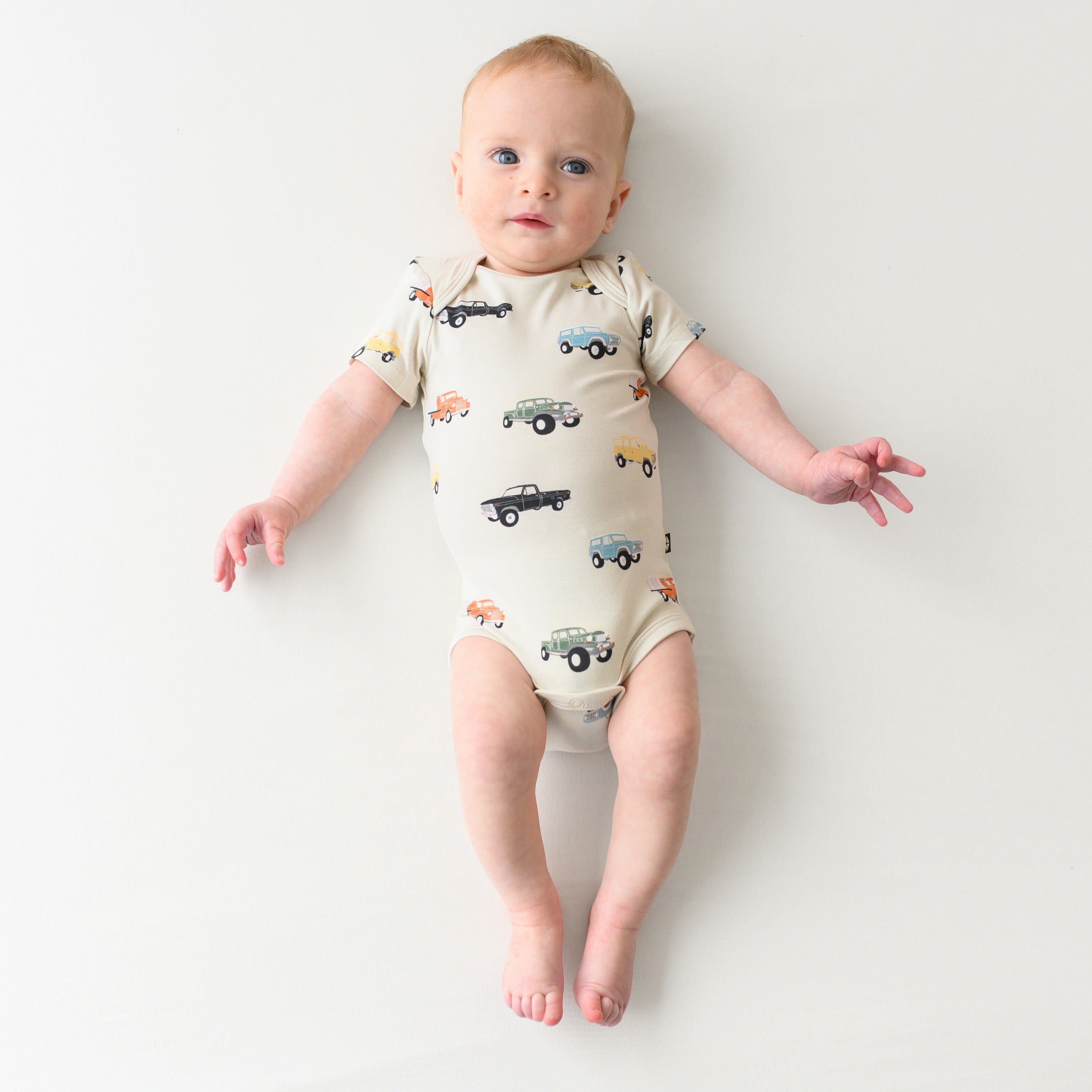 Infant wearing Neutral Bamboo Bodysuit with Vintage Truck Pattern