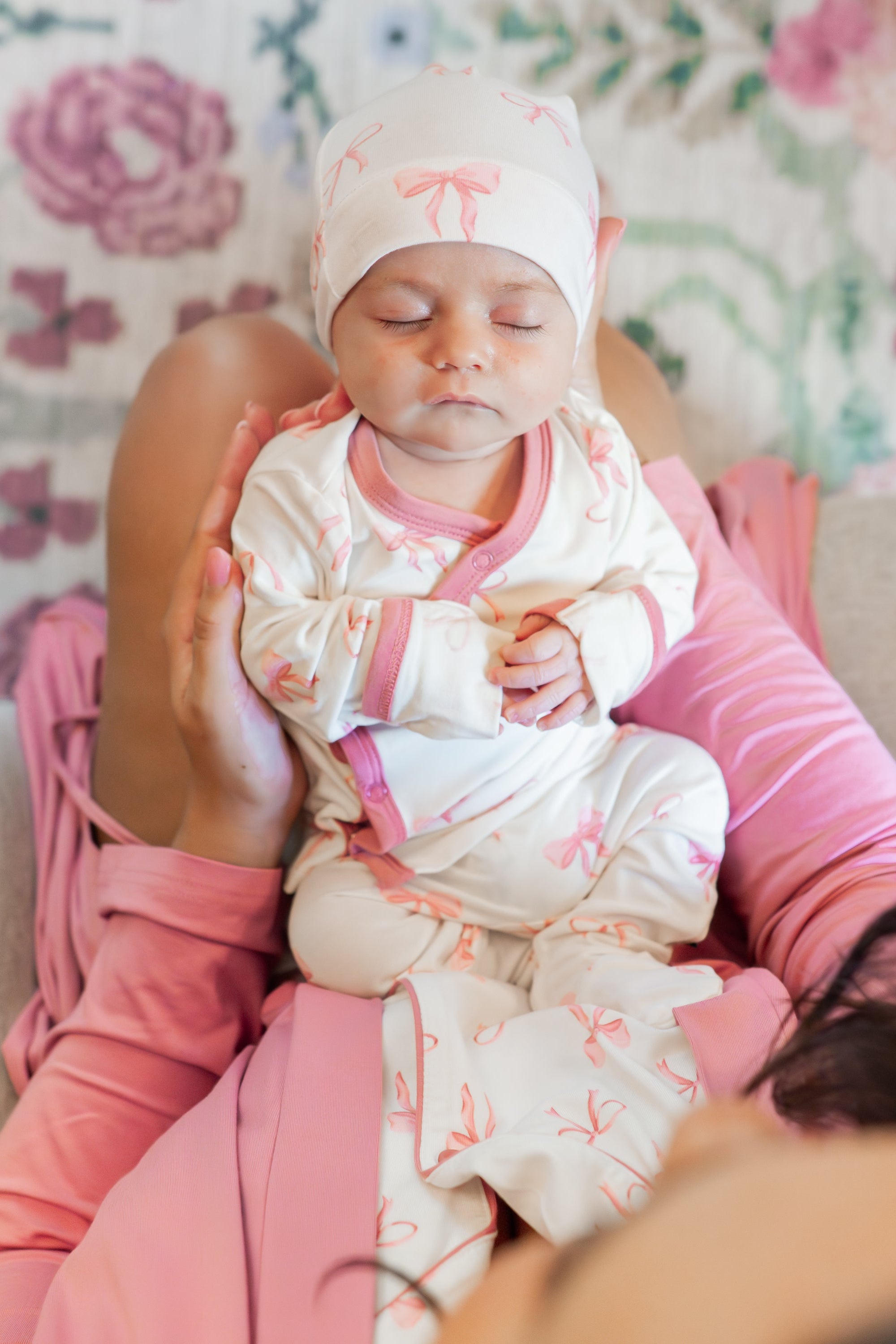 Sleeping newborn laying on mothers lap wearing the Take Me Home Set with Cap in Bow