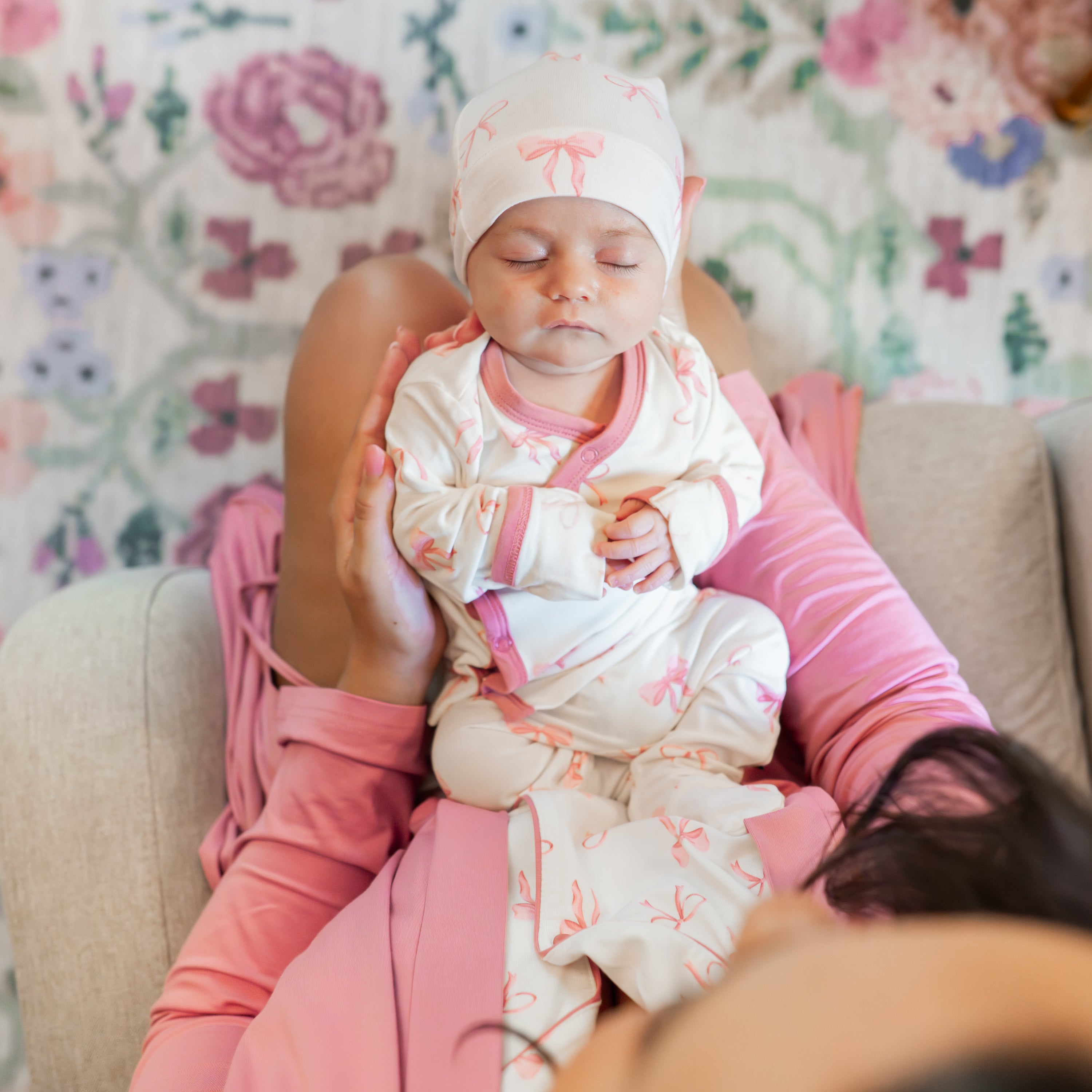 Sleeping newborn laying on mothers lap wearing the Take Me Home Set with Cap in Bow