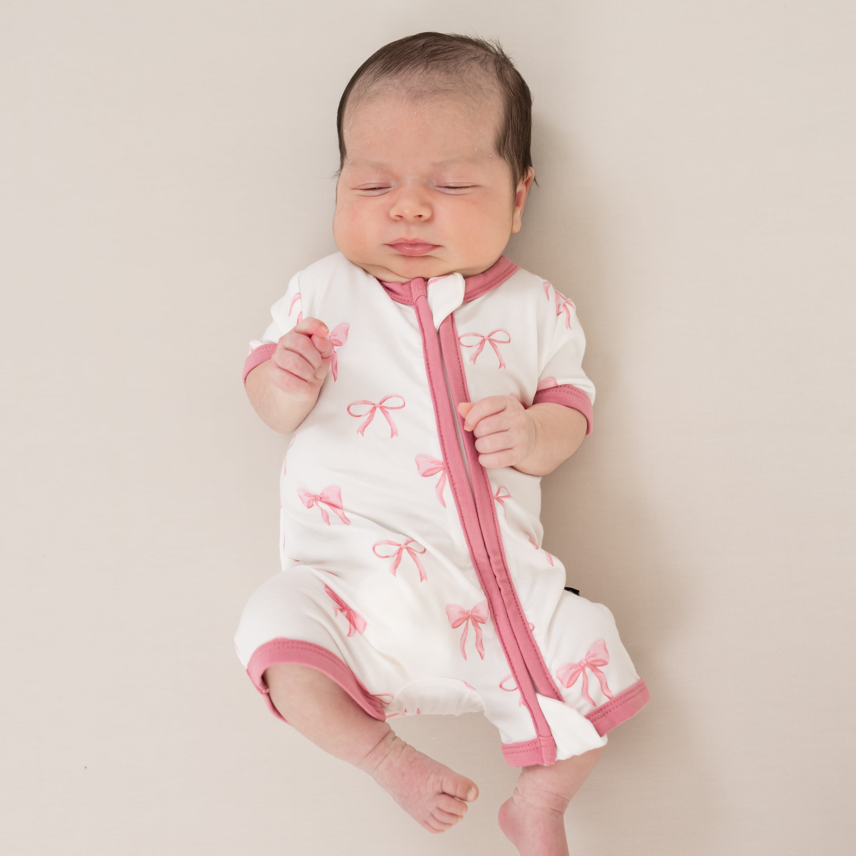 Infant wearing Kyte Baby Zippered Shortall Romper in Bow