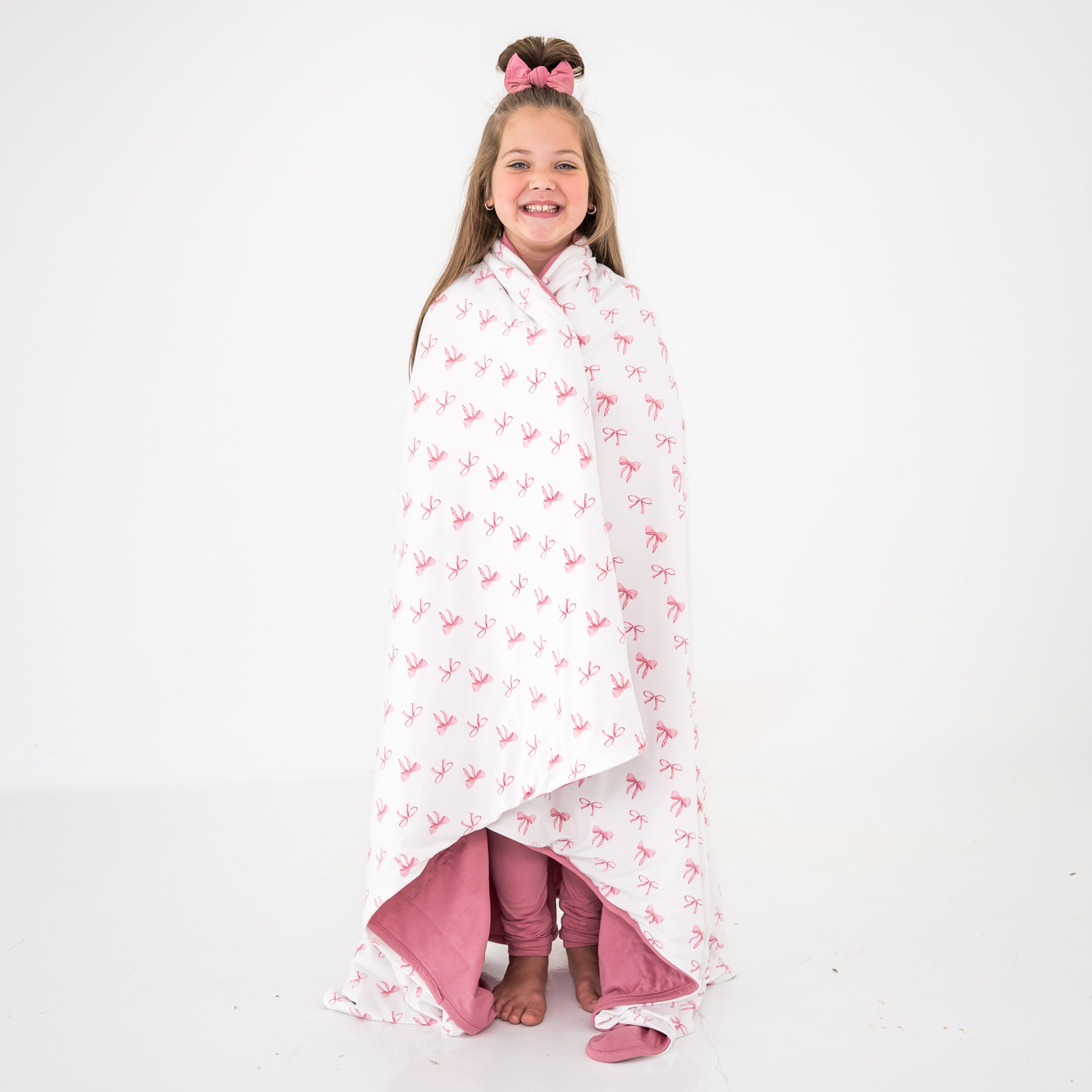 Child wrapped in a blanket with a pink bow pattern