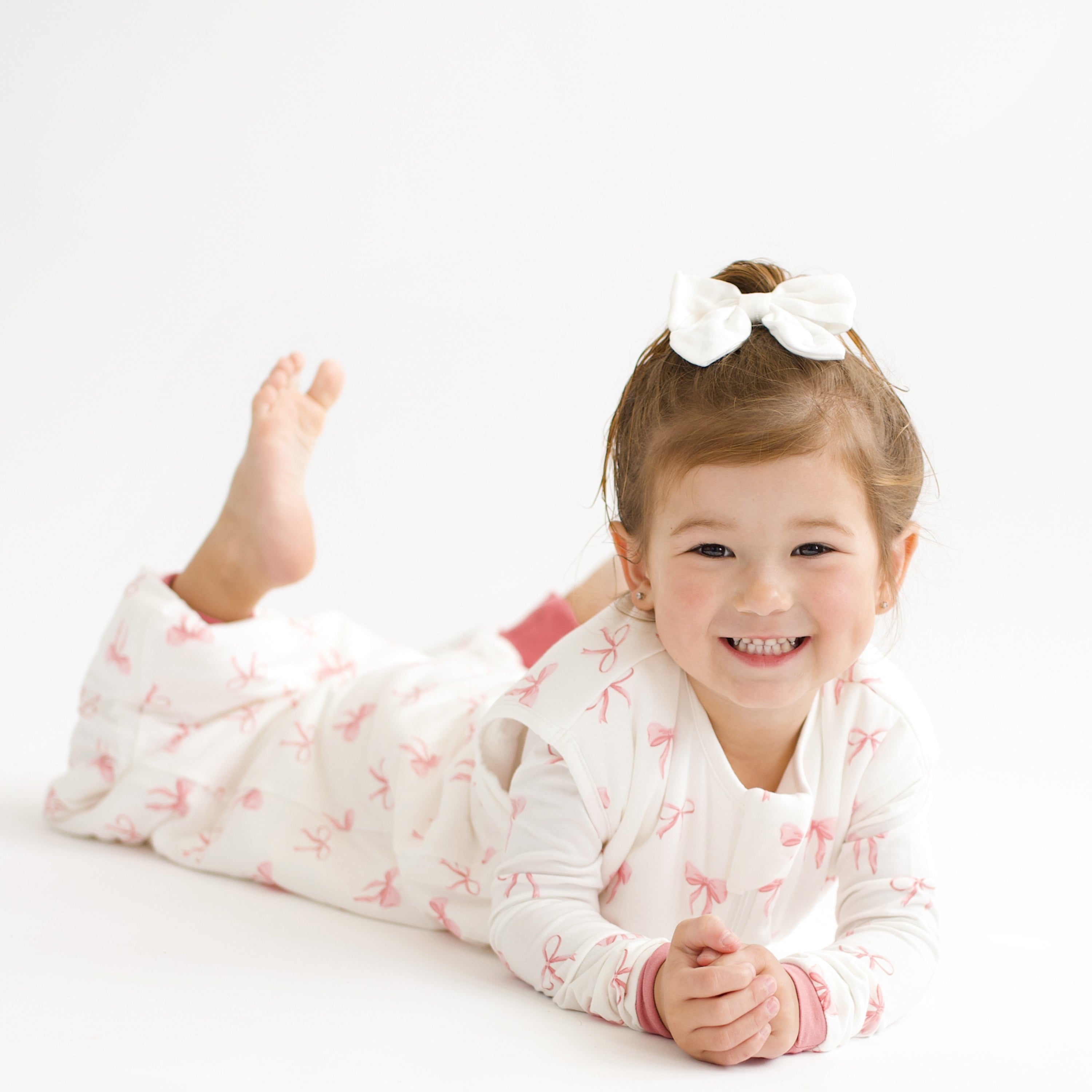 Toddler modeling Sleep Bag Walker in Bow 1.0 laying on stomach with feet up