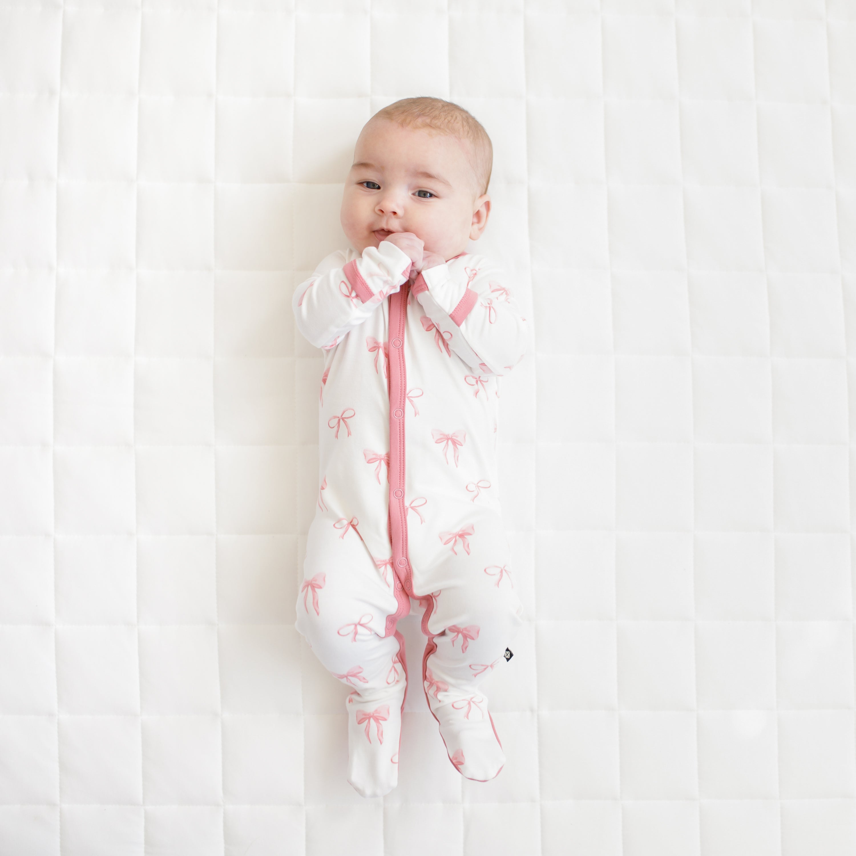 Baby wearing Footie pink pajamas in Bow