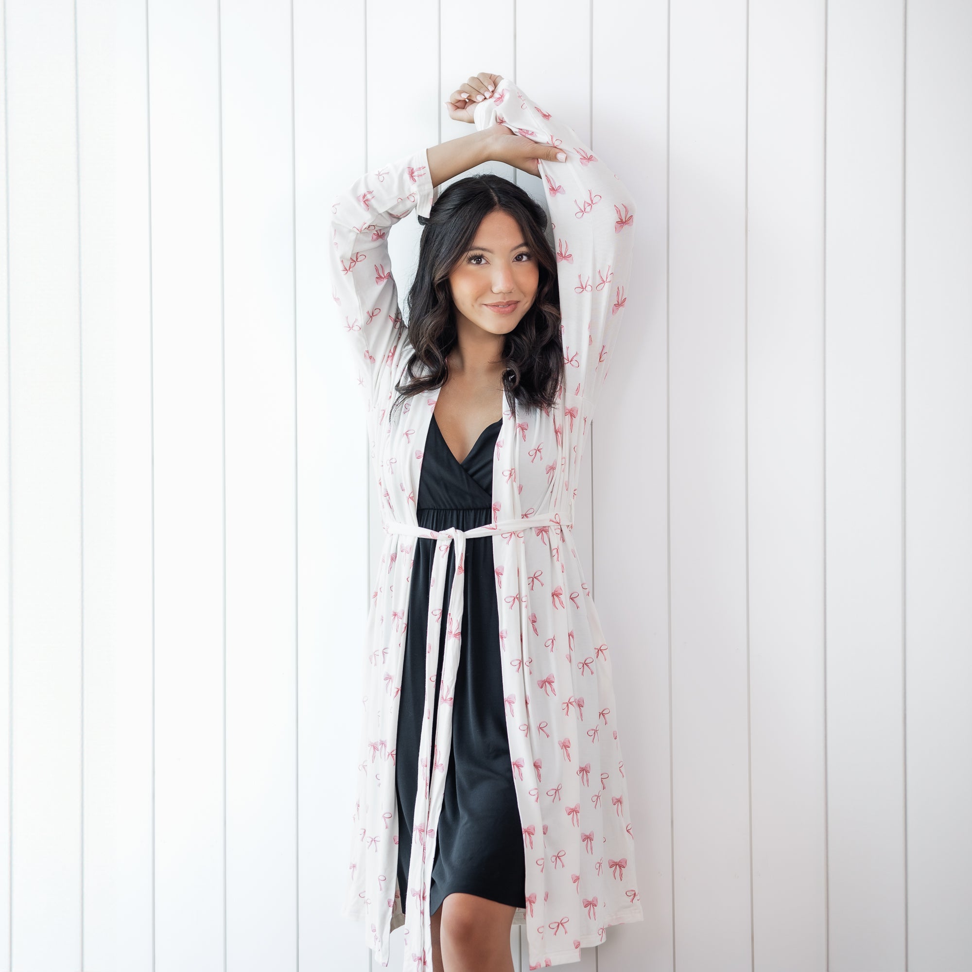 Woman in black nightgown and white robe with pink bow print