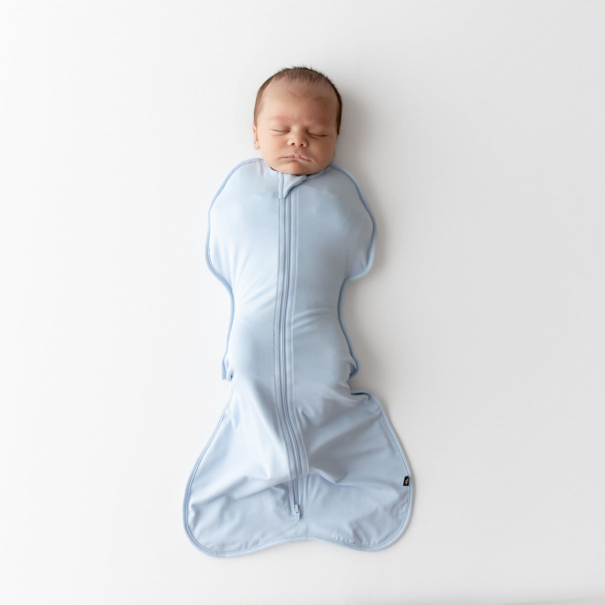Newborn baby wrapped in a blue swaddle bag on a white background