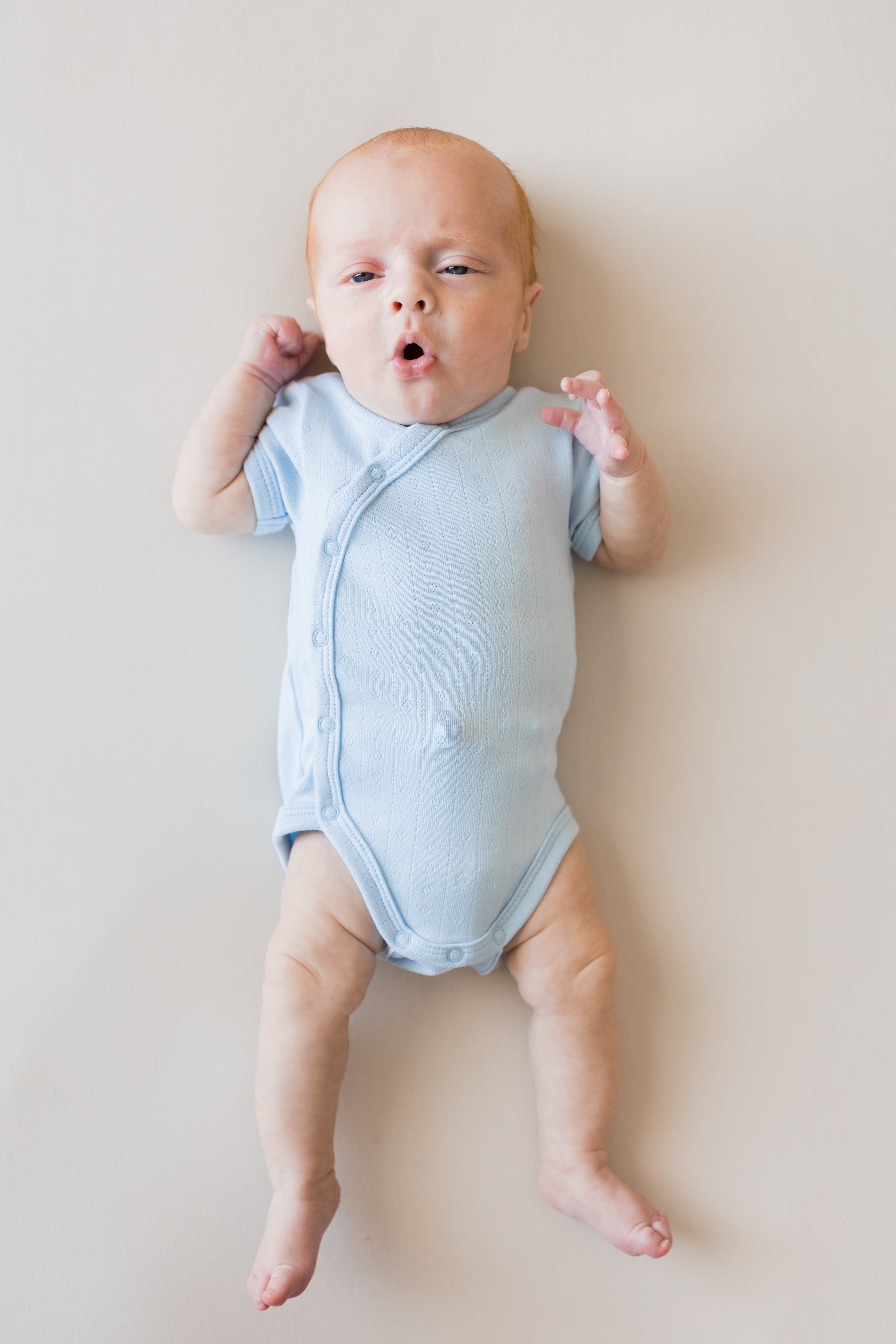 Baby wearing Pointelle Kimono Bodysuit in Breeze color on a beige background