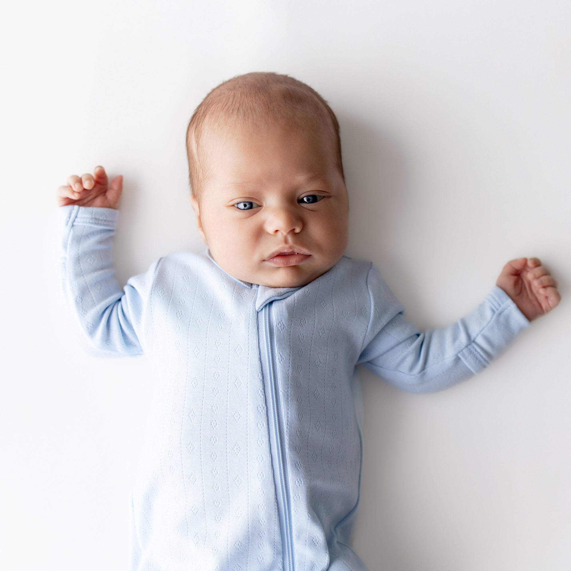 Close up of the Pointelle Zippered Footie in Breeze shown on a newborn model