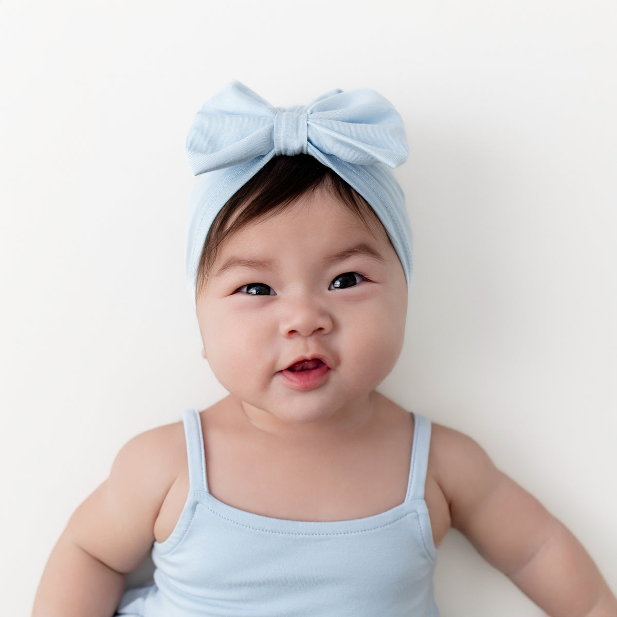 Close up on an infant wearing the Bow Headwrap in Breeze