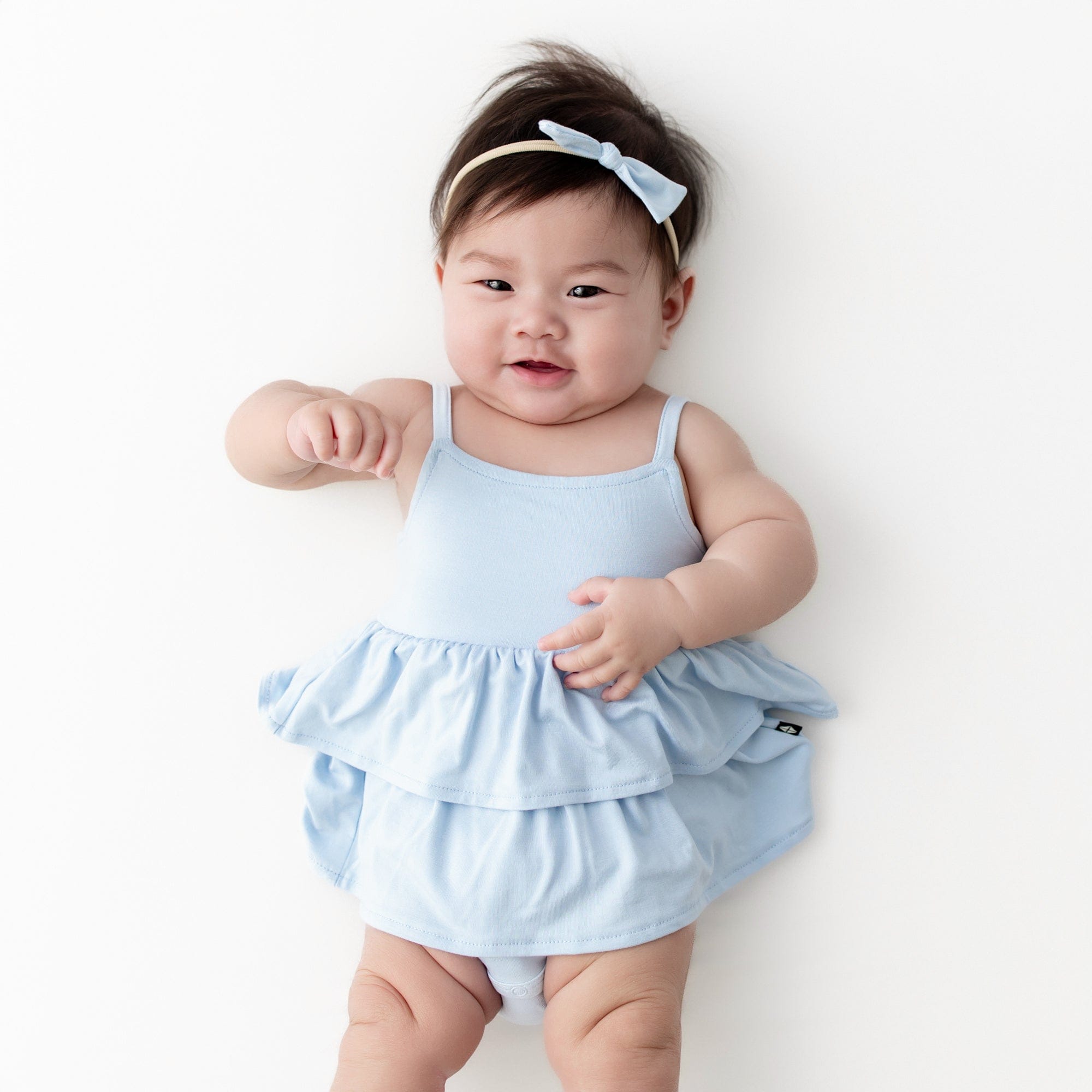 Infant wearing the Spaghetti Strap Ruffle Romper in Breeze with matching tiny nylon bow