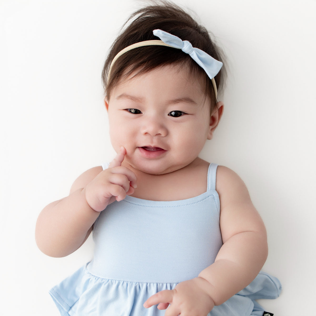 Close up of infant wearing the Tiny Nylon Bow in Breeze and matching spaghetti strap ruffle romper