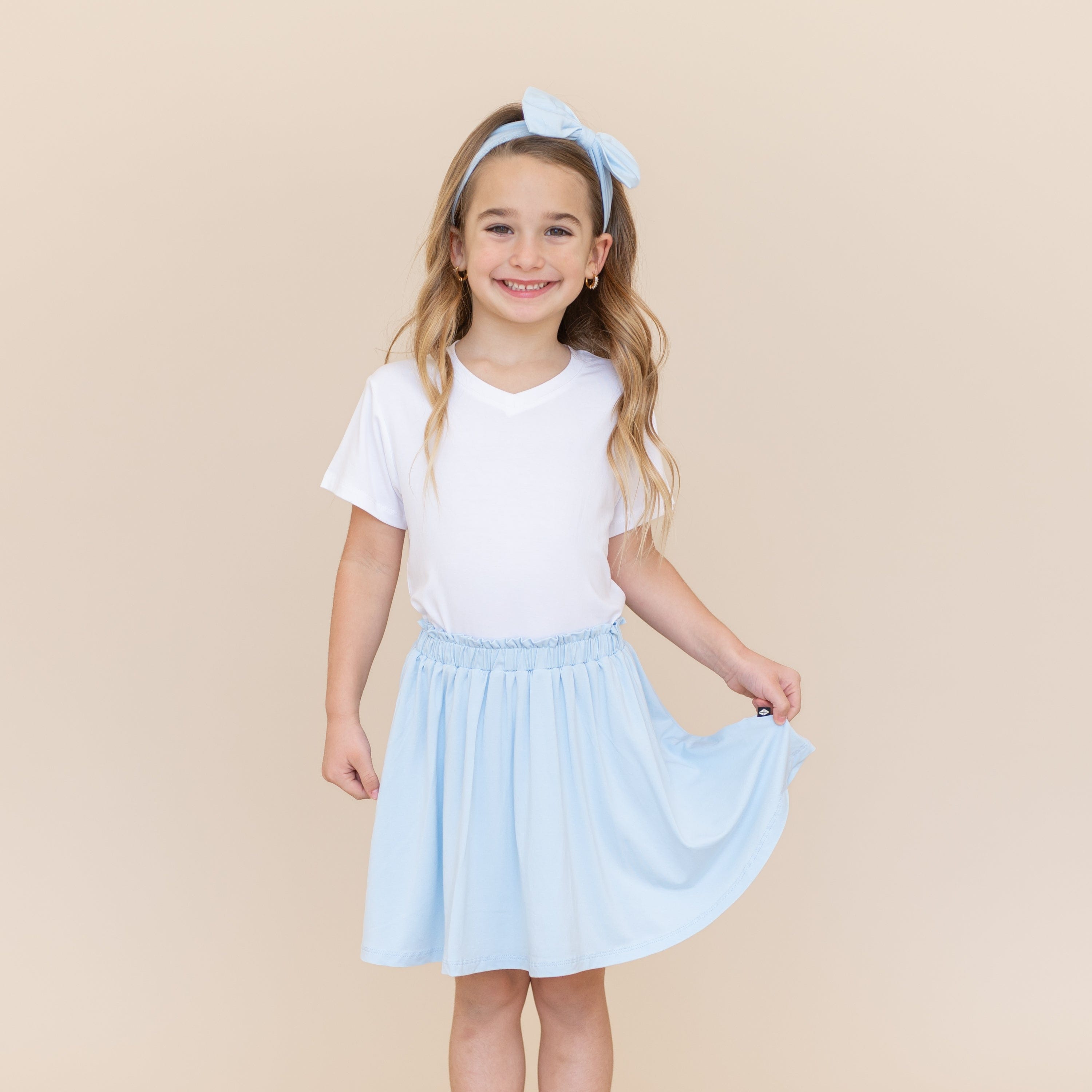 Smiling model wearing the Toddler Skort in Breeze with a white v-neck