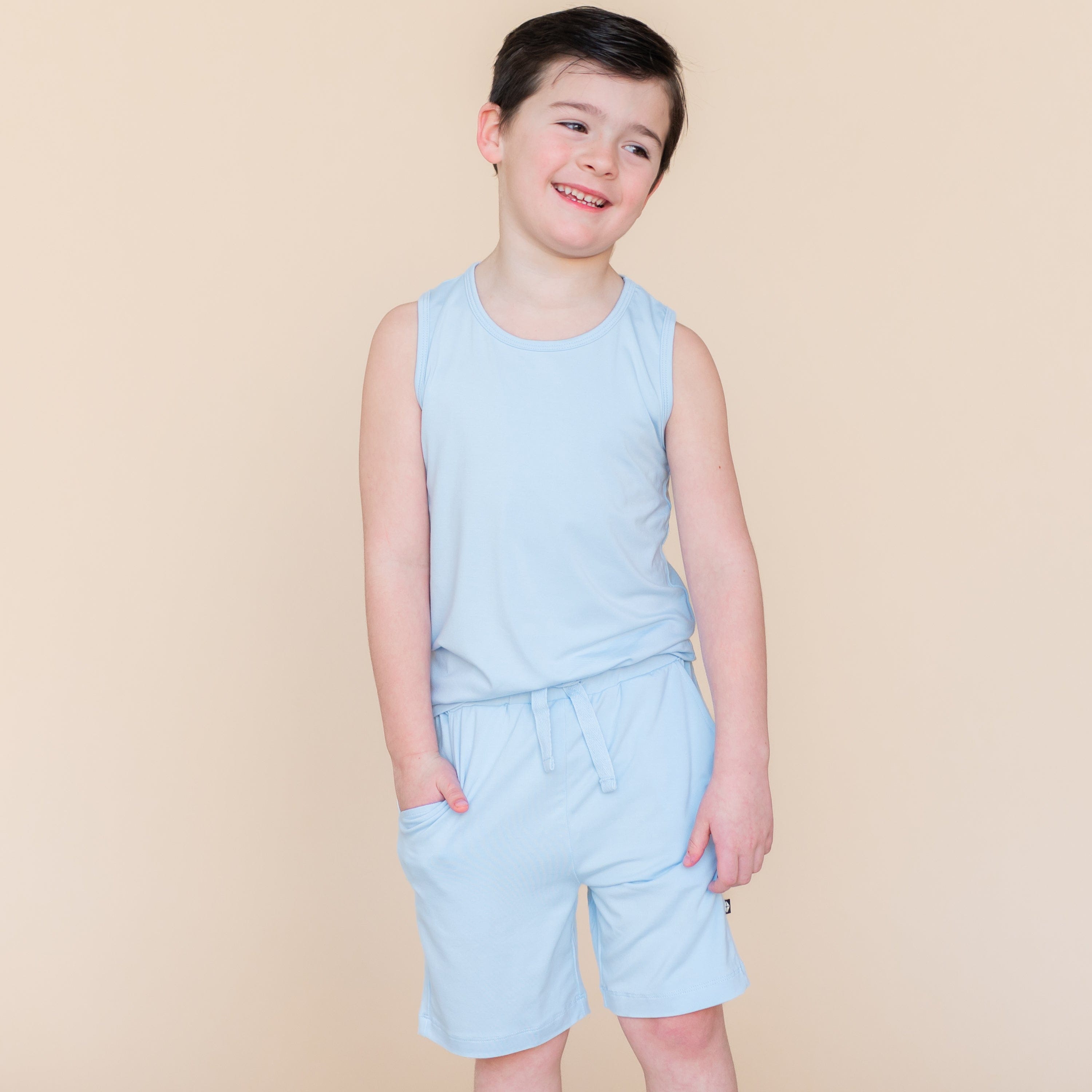 Smiling boy standing wearing the Drawstring Short in Breeze and matching toddler tank top