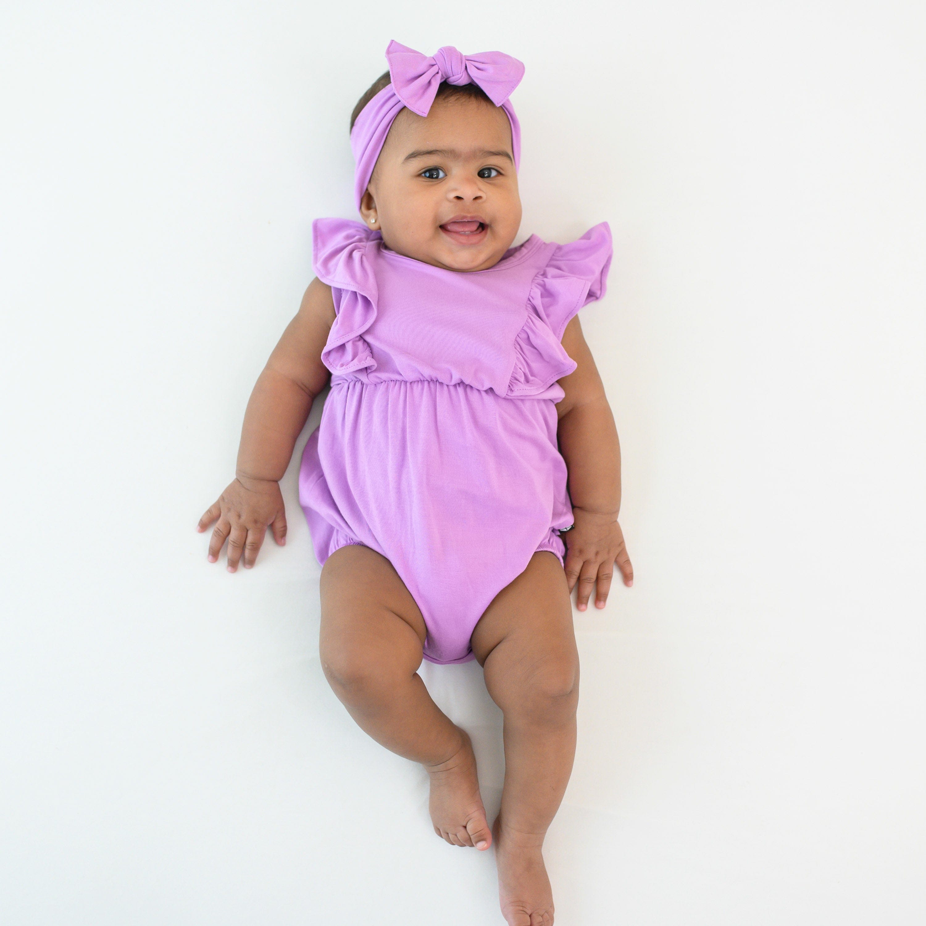 Baby wearing Poi purple bubble romper and bow headband