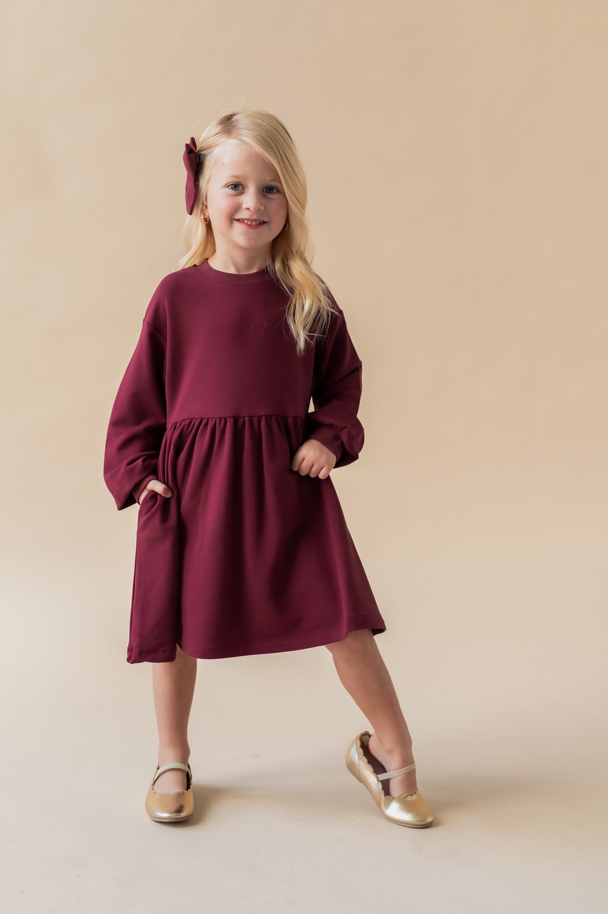 Girl posing in Long Sleeve Skater Dress in Burgundy color on a beige background