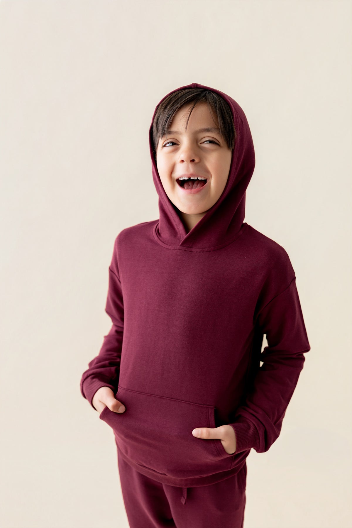 Boy wearing Hoodie in Burgundy color on a beige background