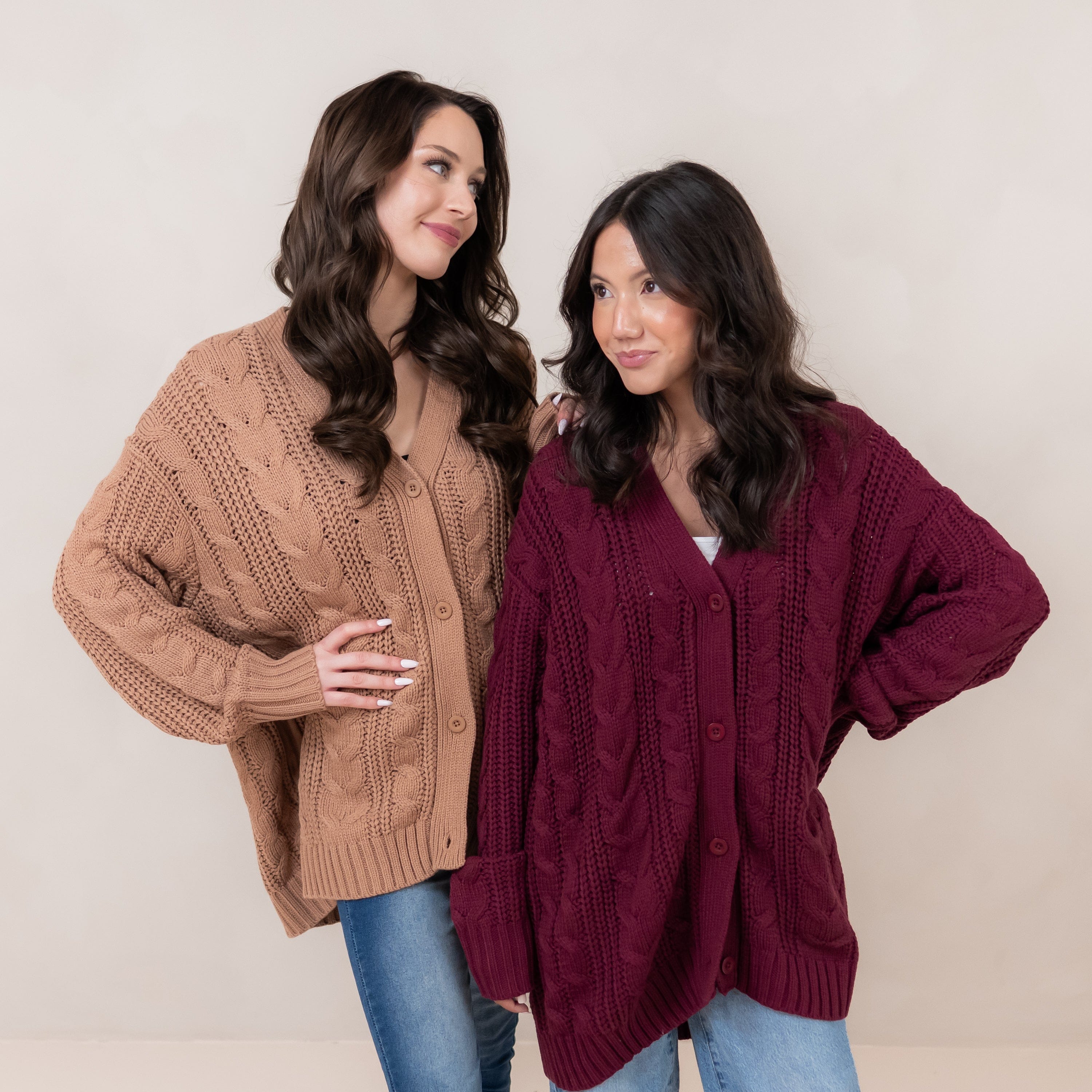 Two female models standing side by side wearing the Cable Knit Adult Cardigan in Burgundy and Latte