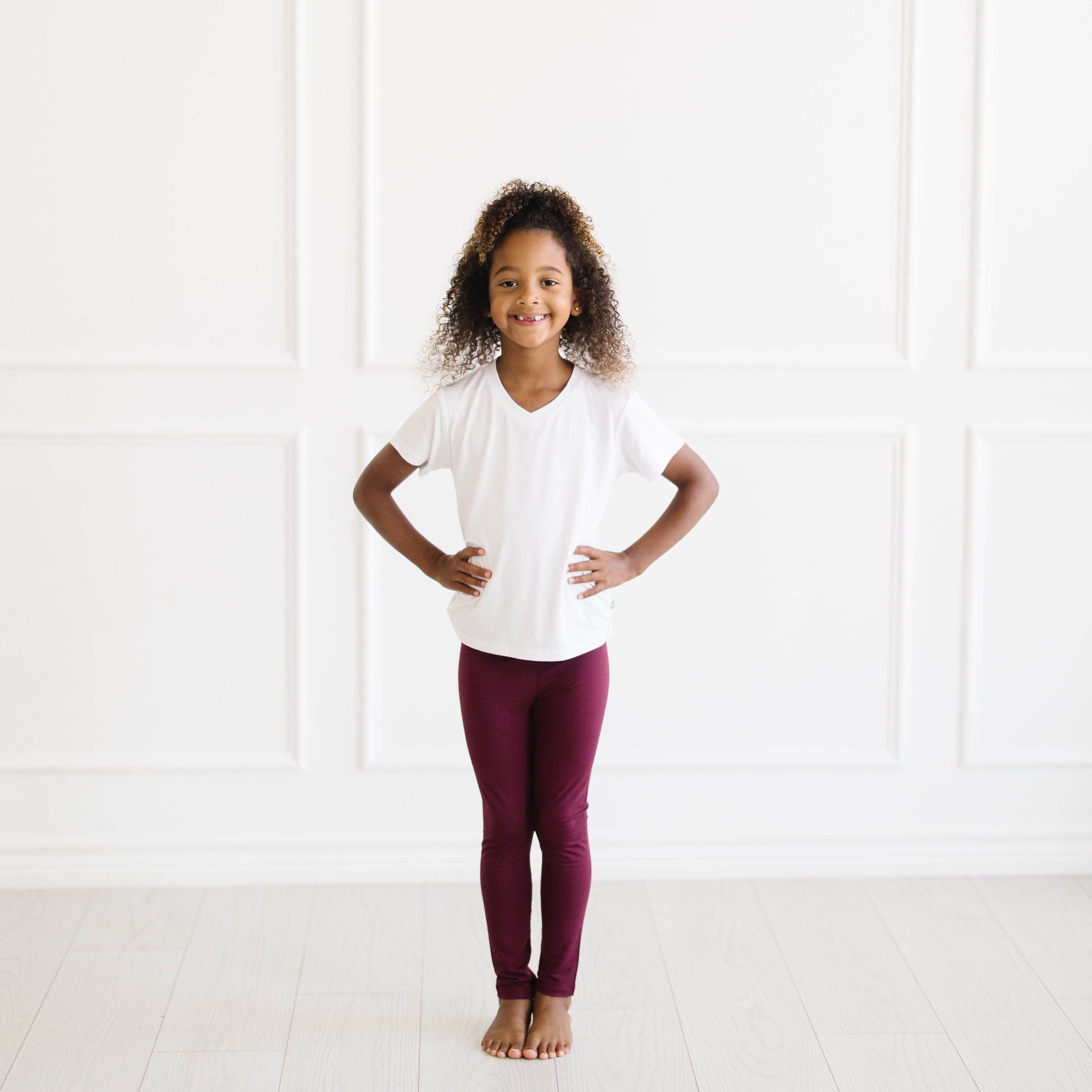 Smiling girl wearing the Toddler Leggings in Burgundy paired with a Snow V-neck