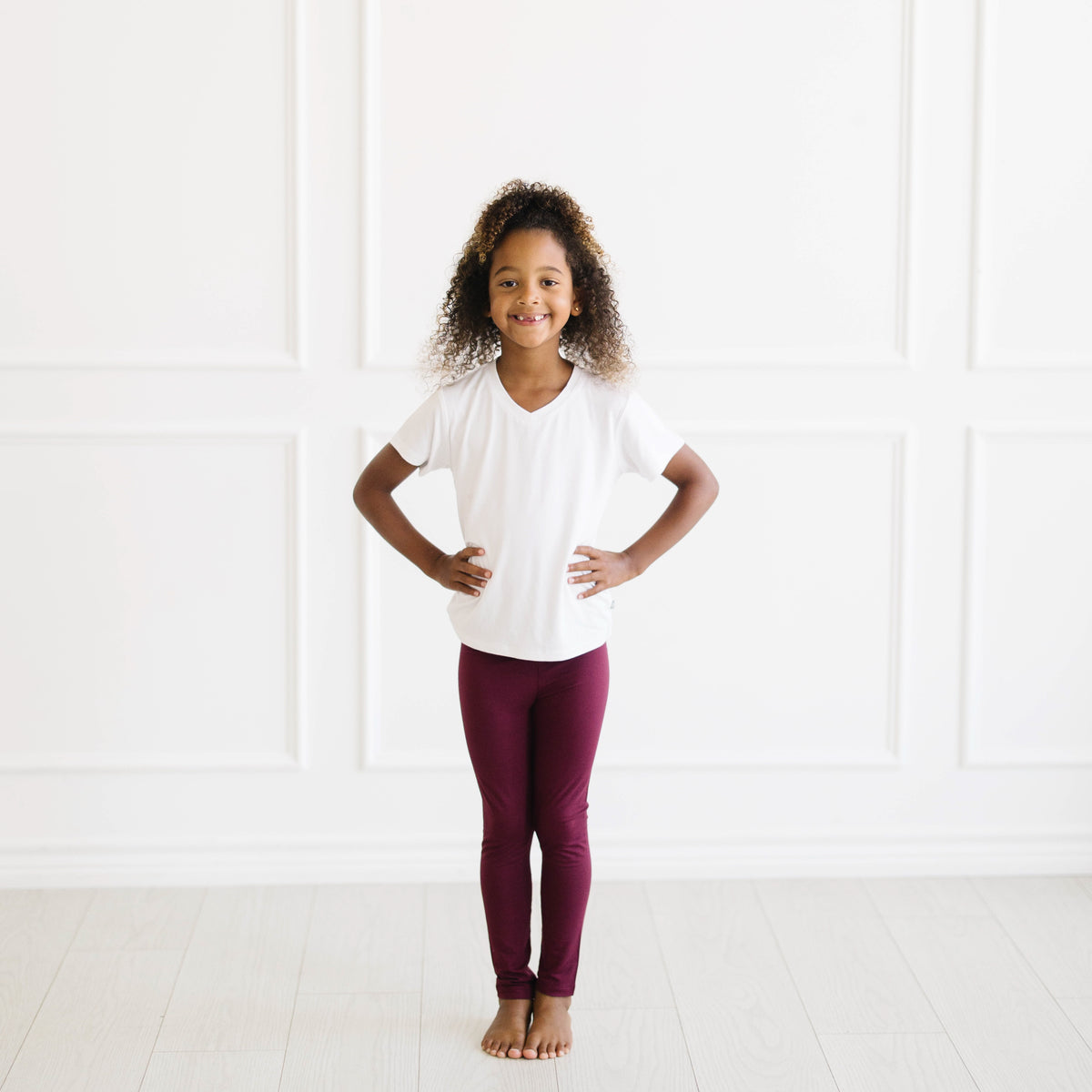 Smiling girl wearing the Toddler Leggings in Burgundy paired with a Snow V-neck