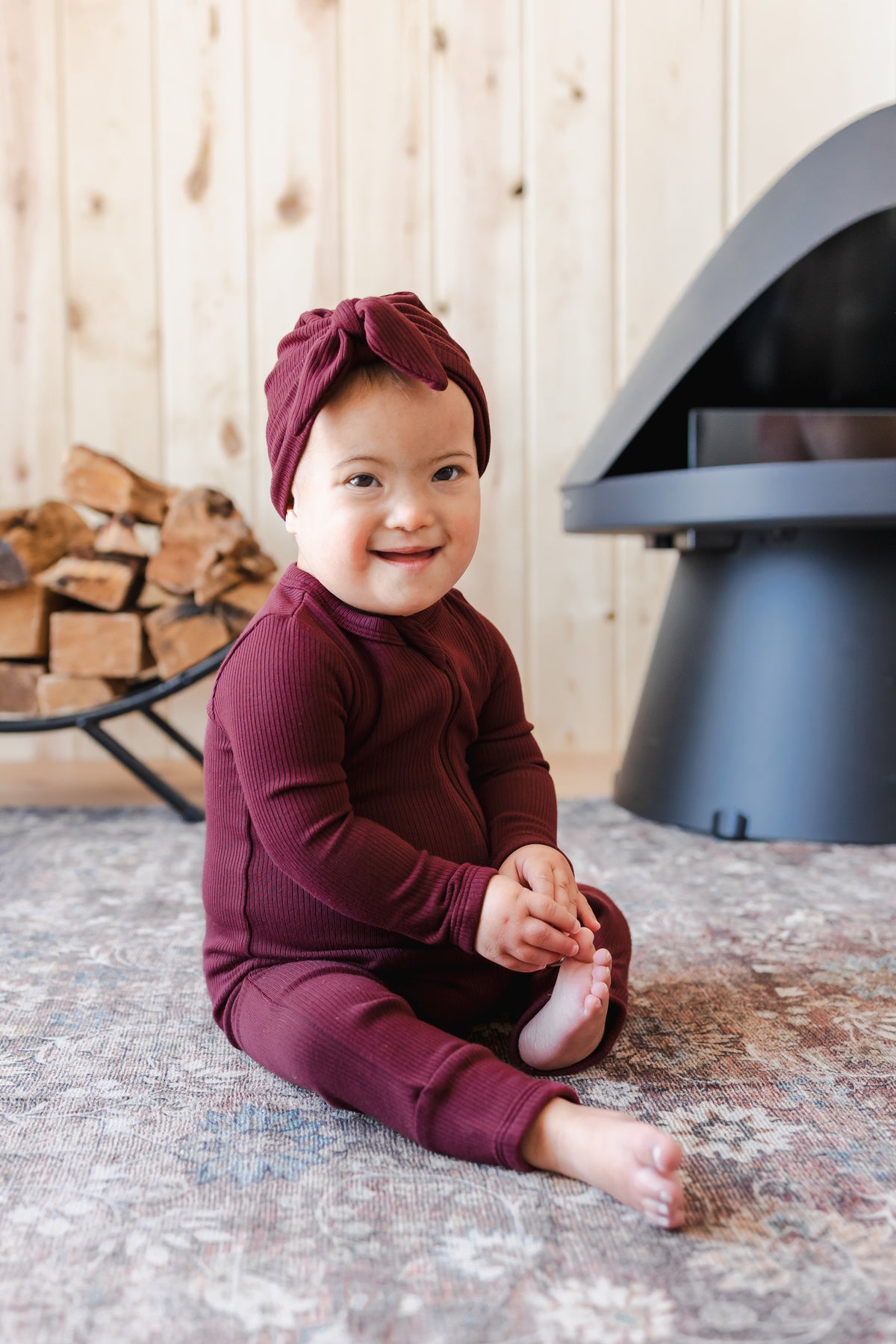 Toddler wearing Ribbed Zipper Romper and Ribbed Headwrap in Burgundy sitting on carpet
