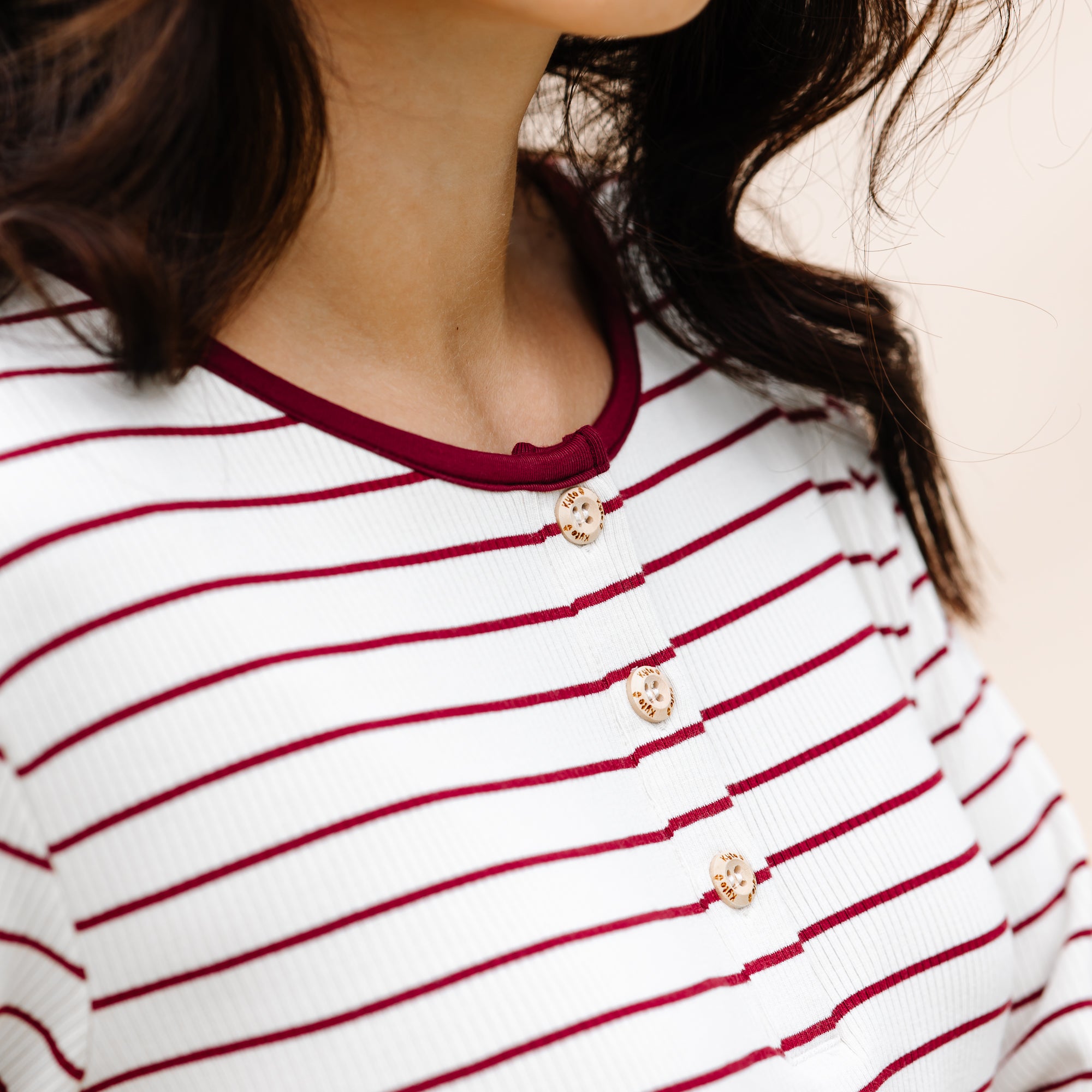 Close up of the button placket showing the Kyte Baby engraved buttons on the Women’s Ribbed Henley Set in Burgundy Stripe