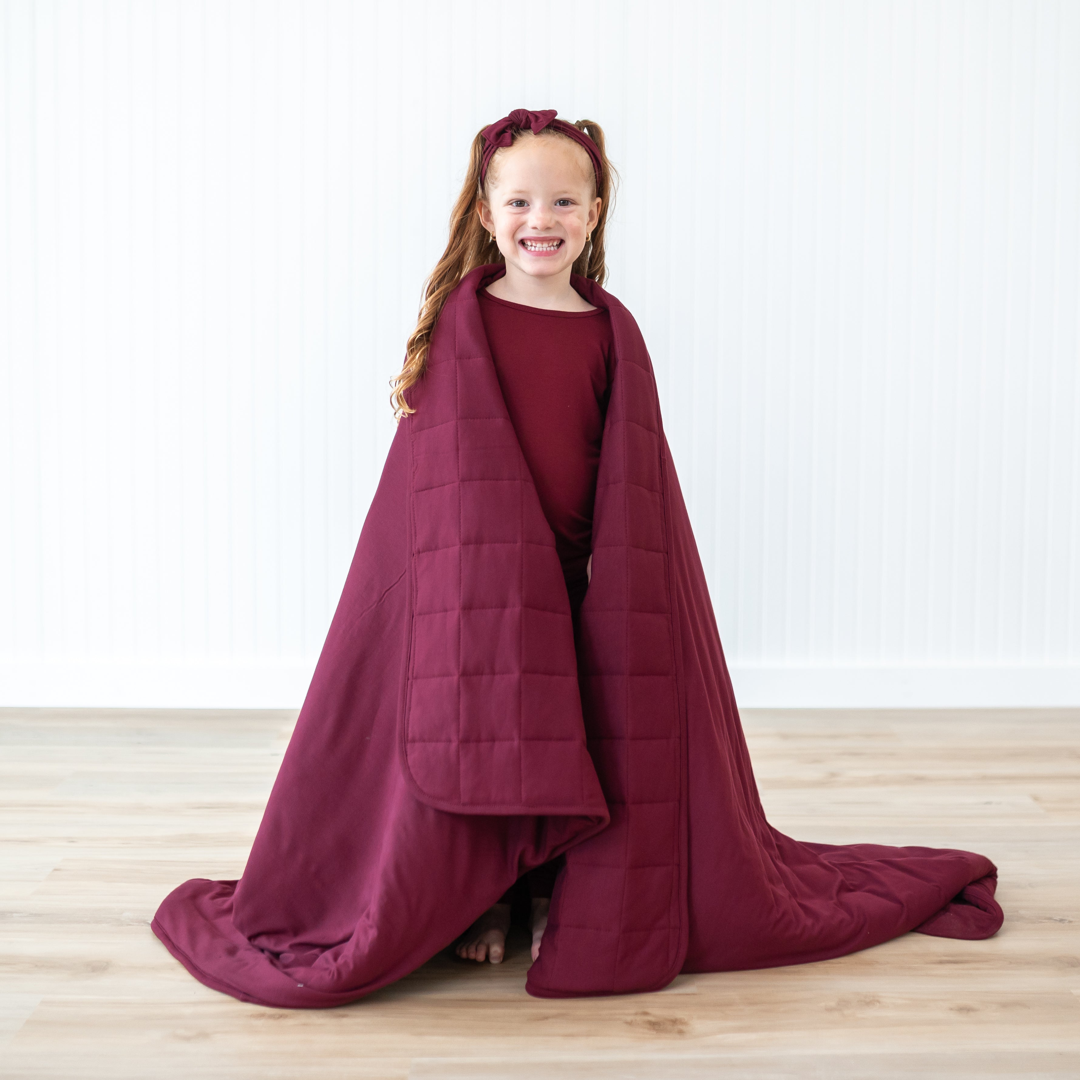 Young girl standing with the Youth Blanket in Burgundy 2.5 wrapped around her