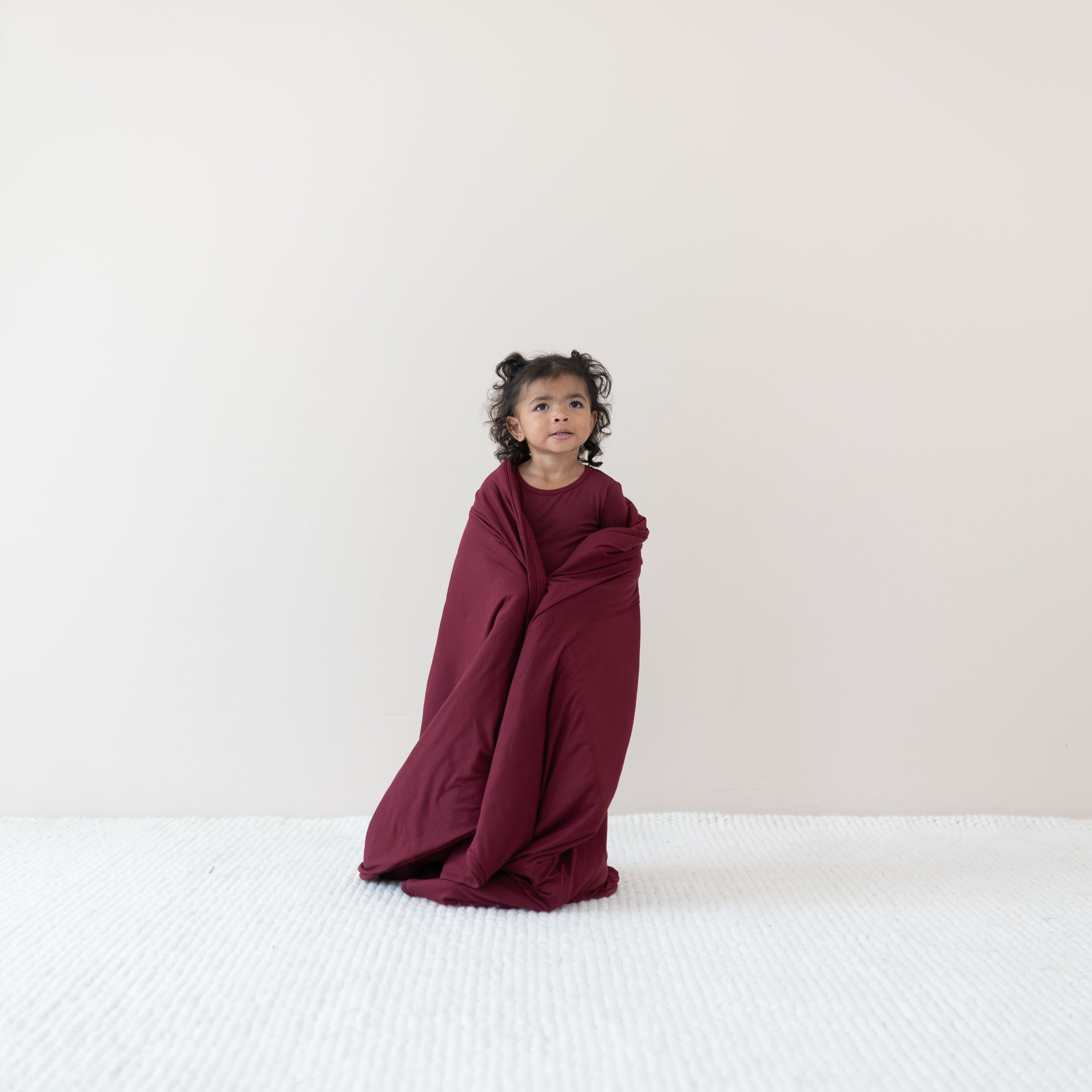 Toddler standing with the Toddler Blanket in Burgundy 2.5 wrapped around her