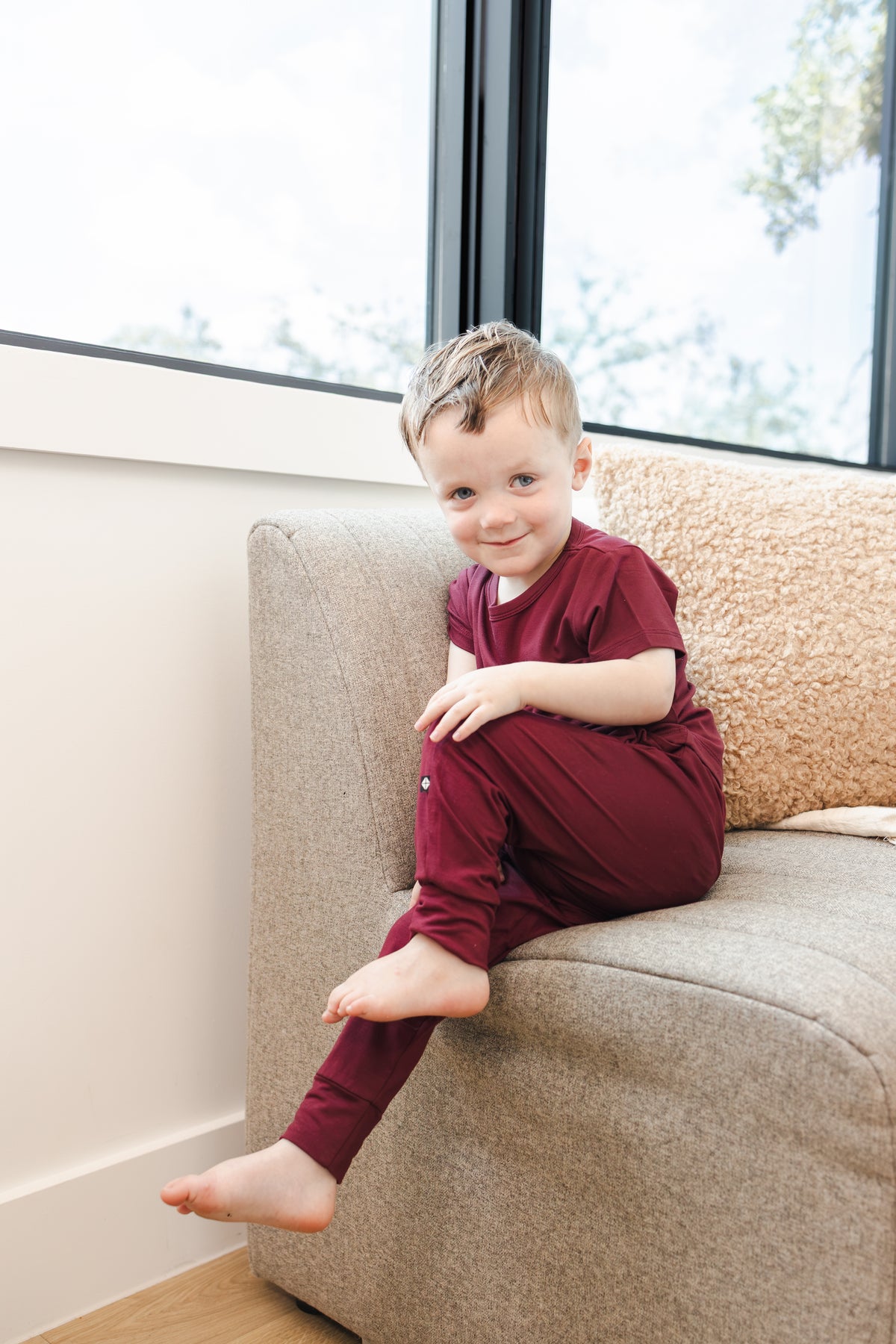 Child wearing Toddler Jogger Pant in Burgundy under Toddler basic tee in burgundy sitting on a sofa