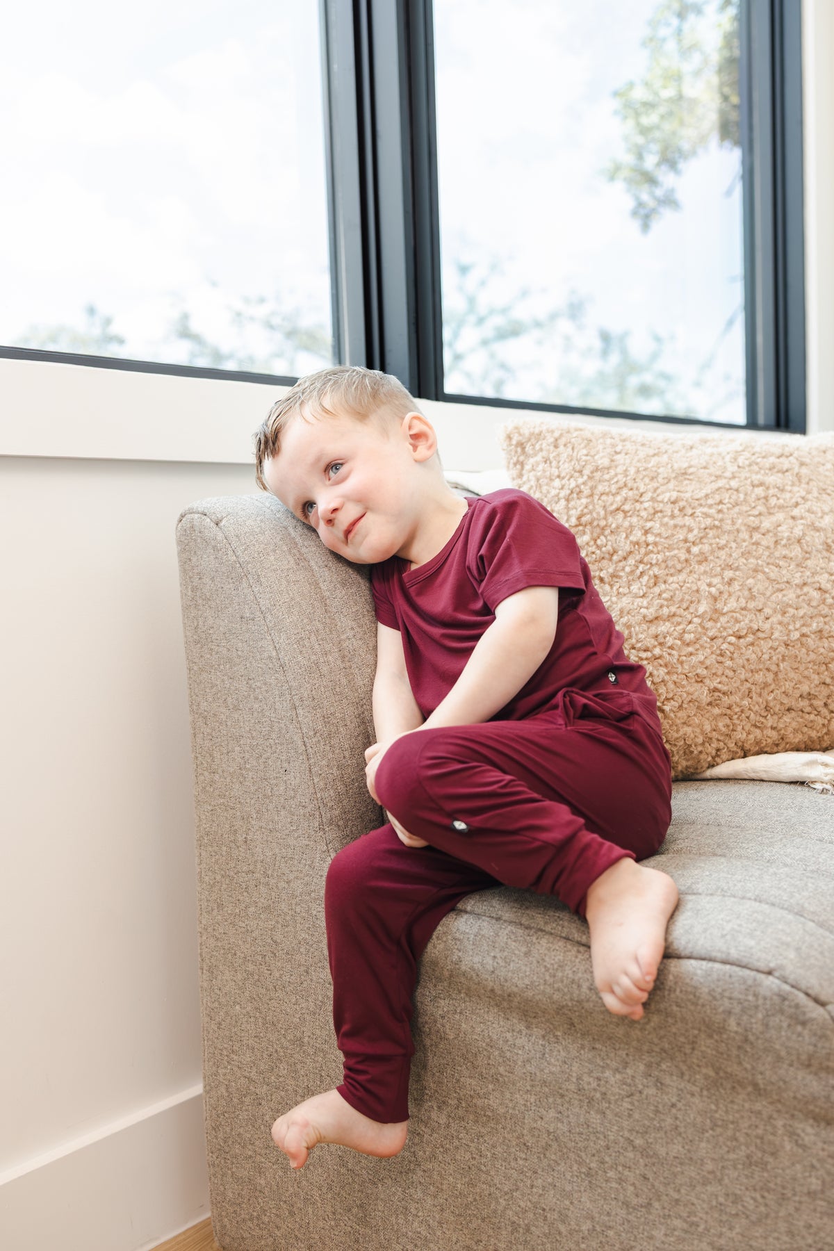 Child wearing Toddler Jogger Pant in Burgundy under Toddler crew neck tee in burgundy sitting on sofa