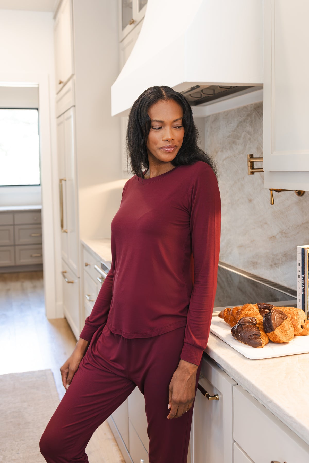 Model wearing Women's Jogger Pajama Set in Burgundy standing against kitchen counter