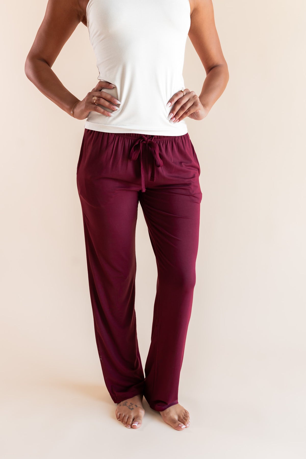Modal wearing Women's Lounge Pants in Burgundy under white camisole on a beige background
