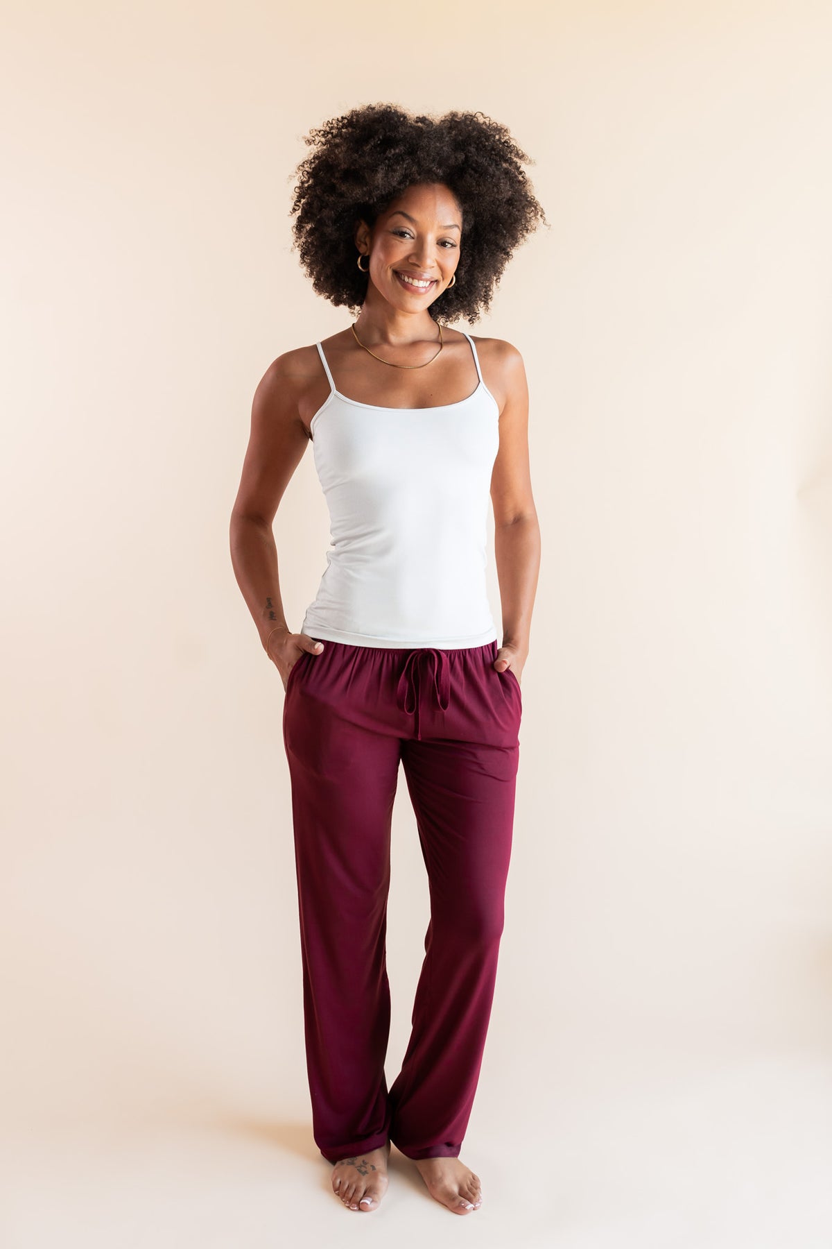 Modal smiling in Women's Lounge Pants in Burgundy under white camisole on a beige background