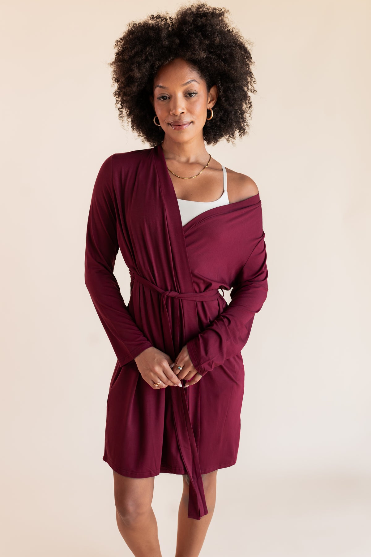 Model wearing Women's Lounge Robe in Burgundy over white bra on a beige background